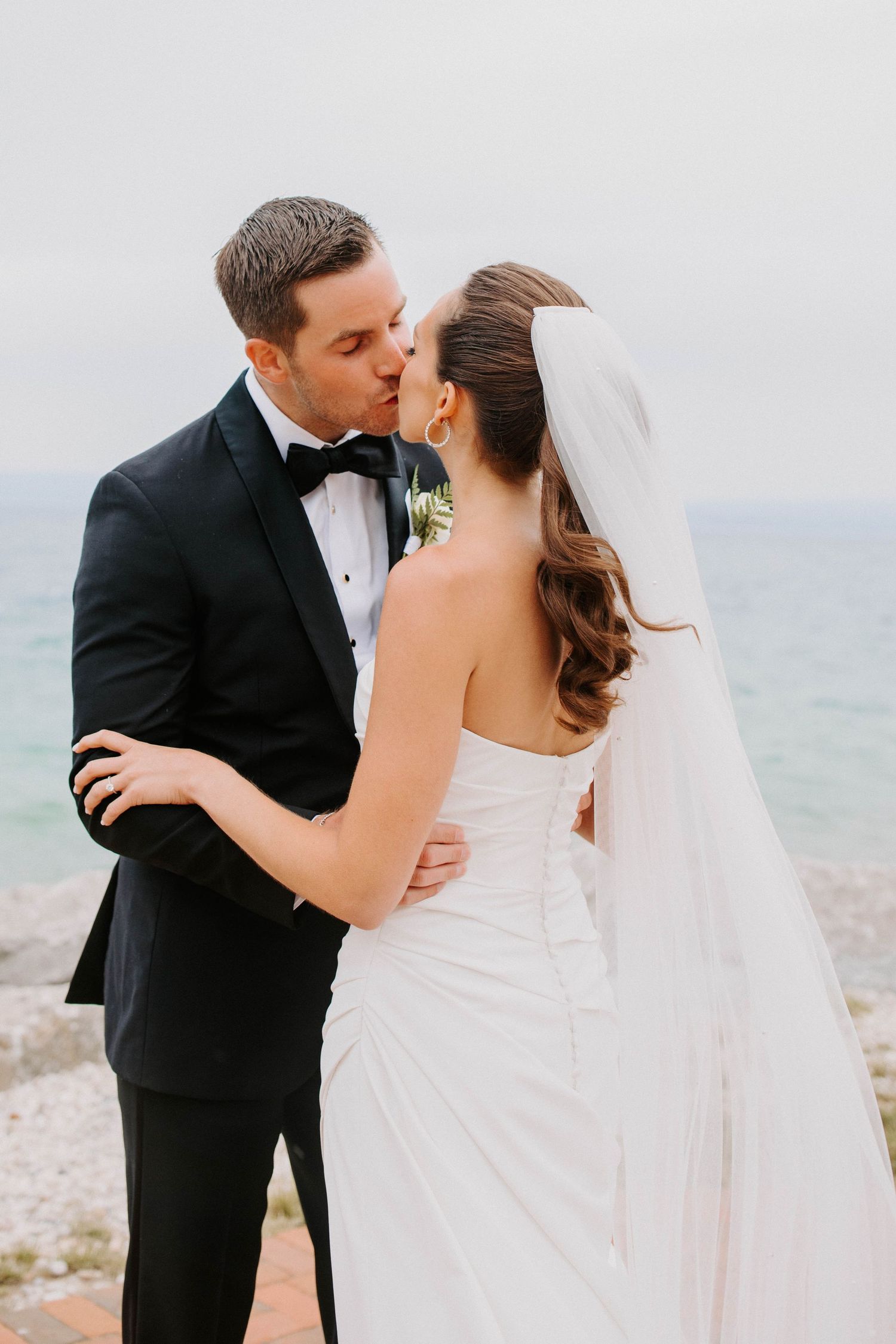Newlyweds share a romantic kiss during their waterfront wedding ceremony.