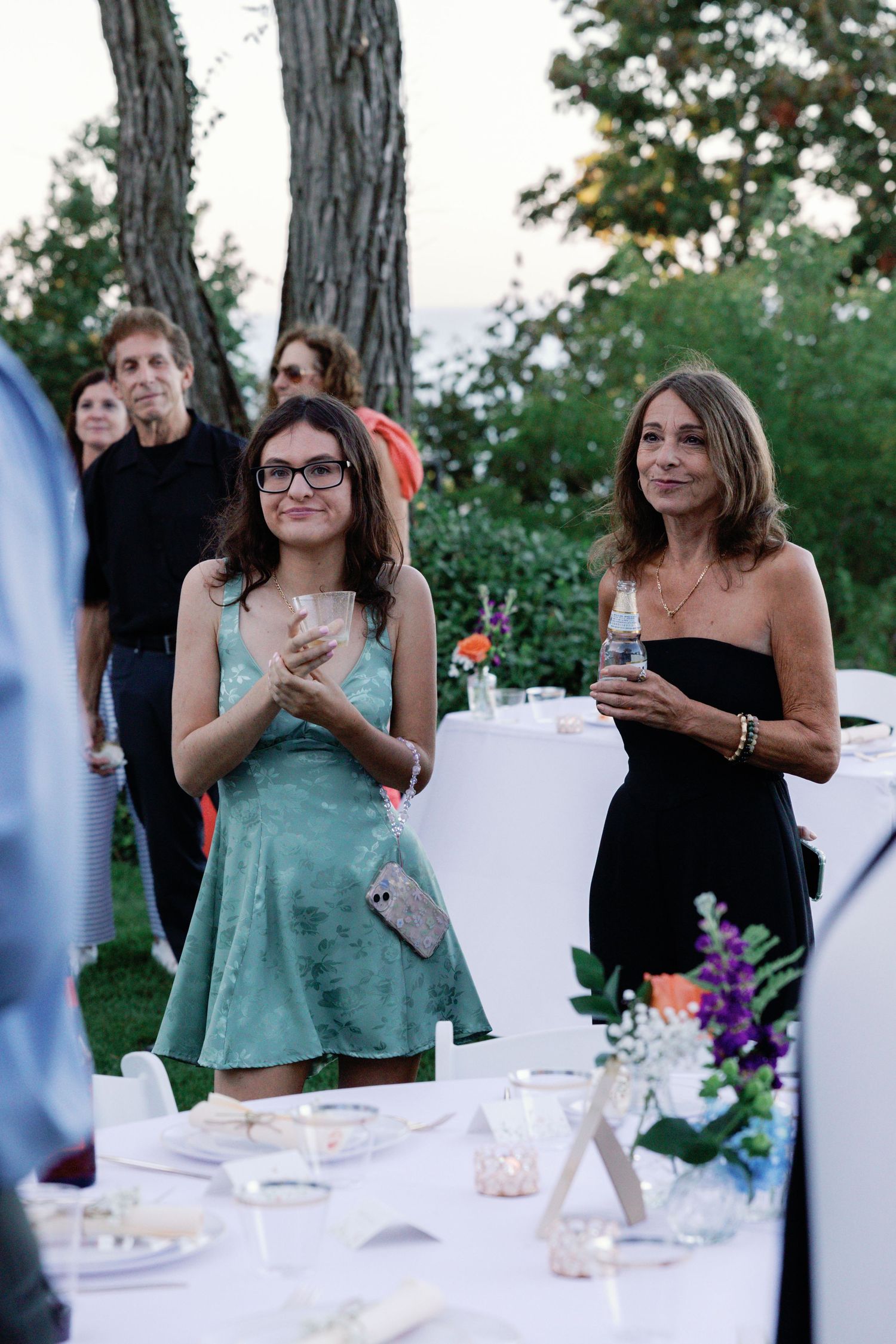 Wedding guests enjoying drinks and conversation at an outdoor reception table.