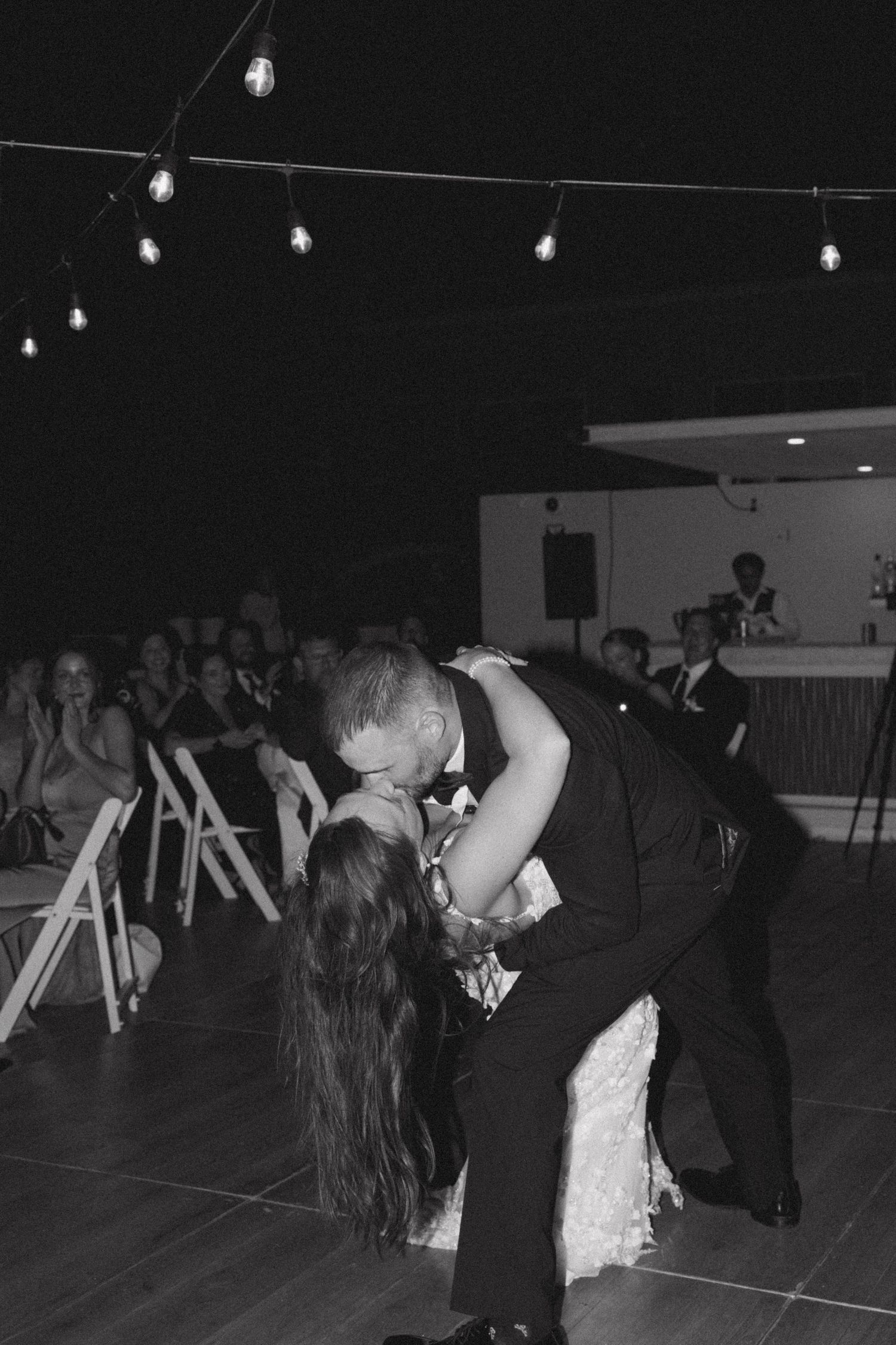 A dramatic dip during a wedding dance under string lights.
