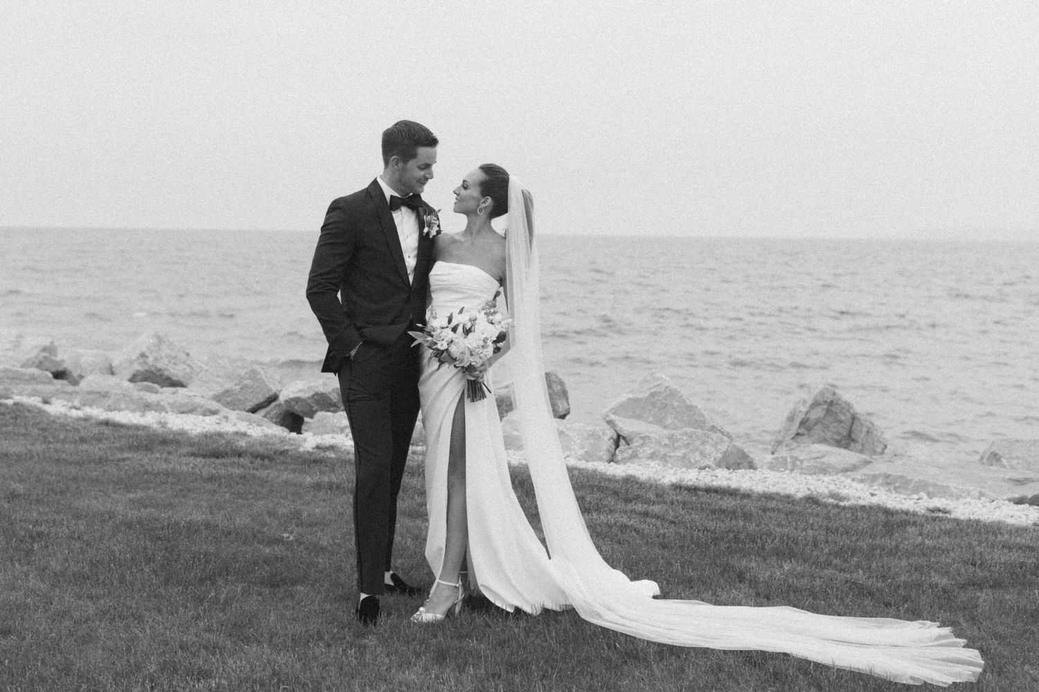 Black and white wedding photography series showing couple by oceanside.