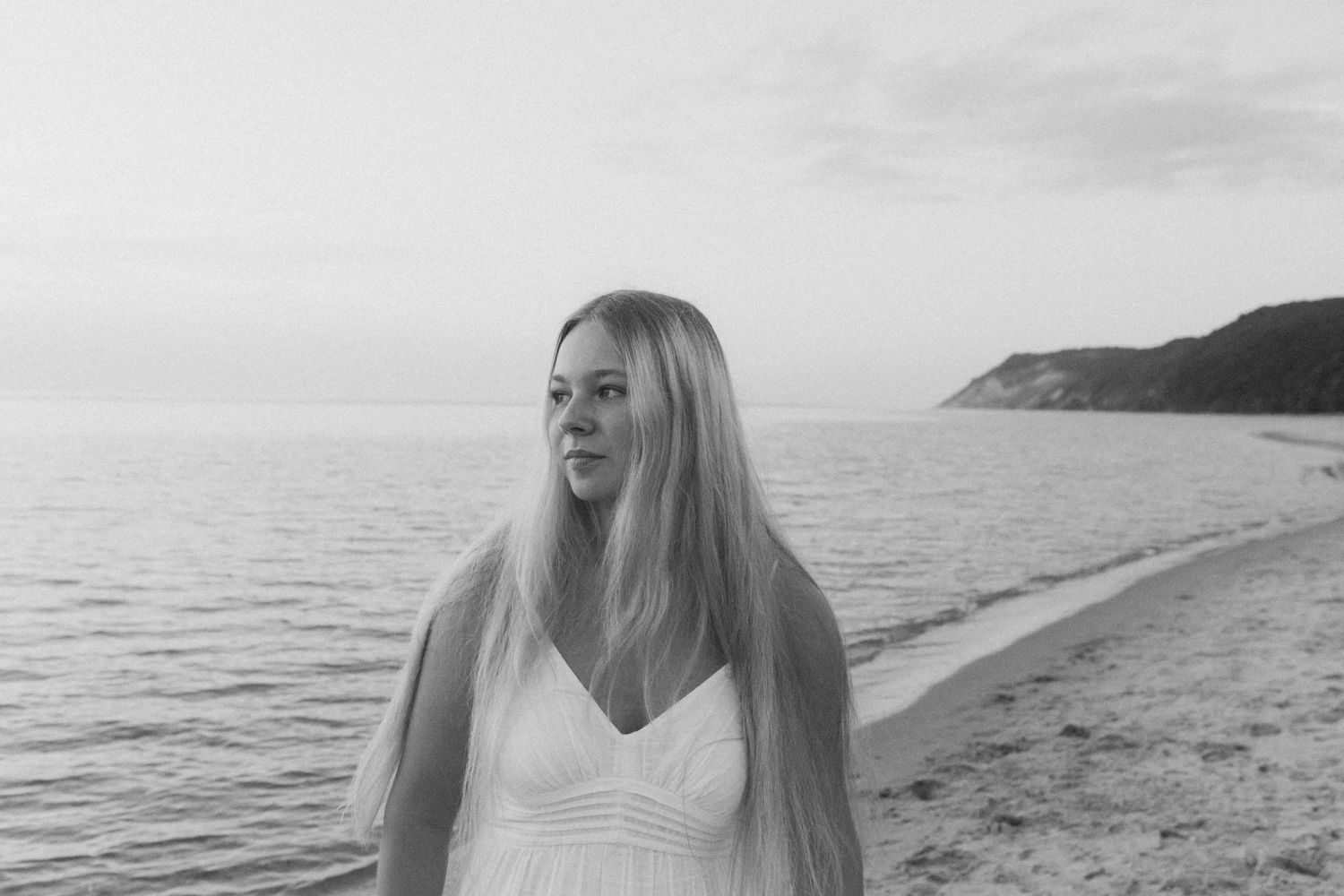 Sunset photoshoot at a scenic beach with calm waters and distant cliffs.