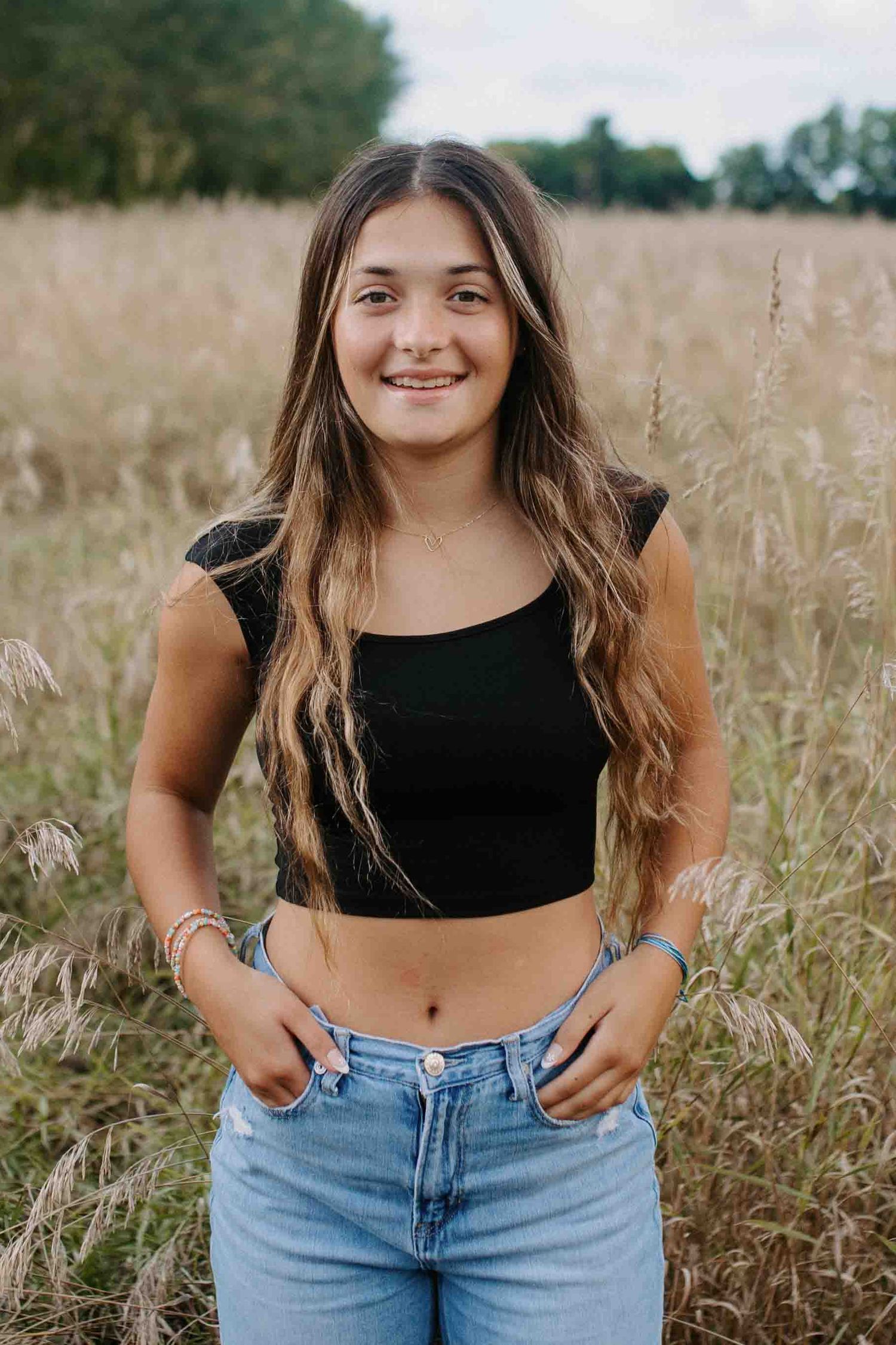 Casual portrait in field wearing black crop top and denim.