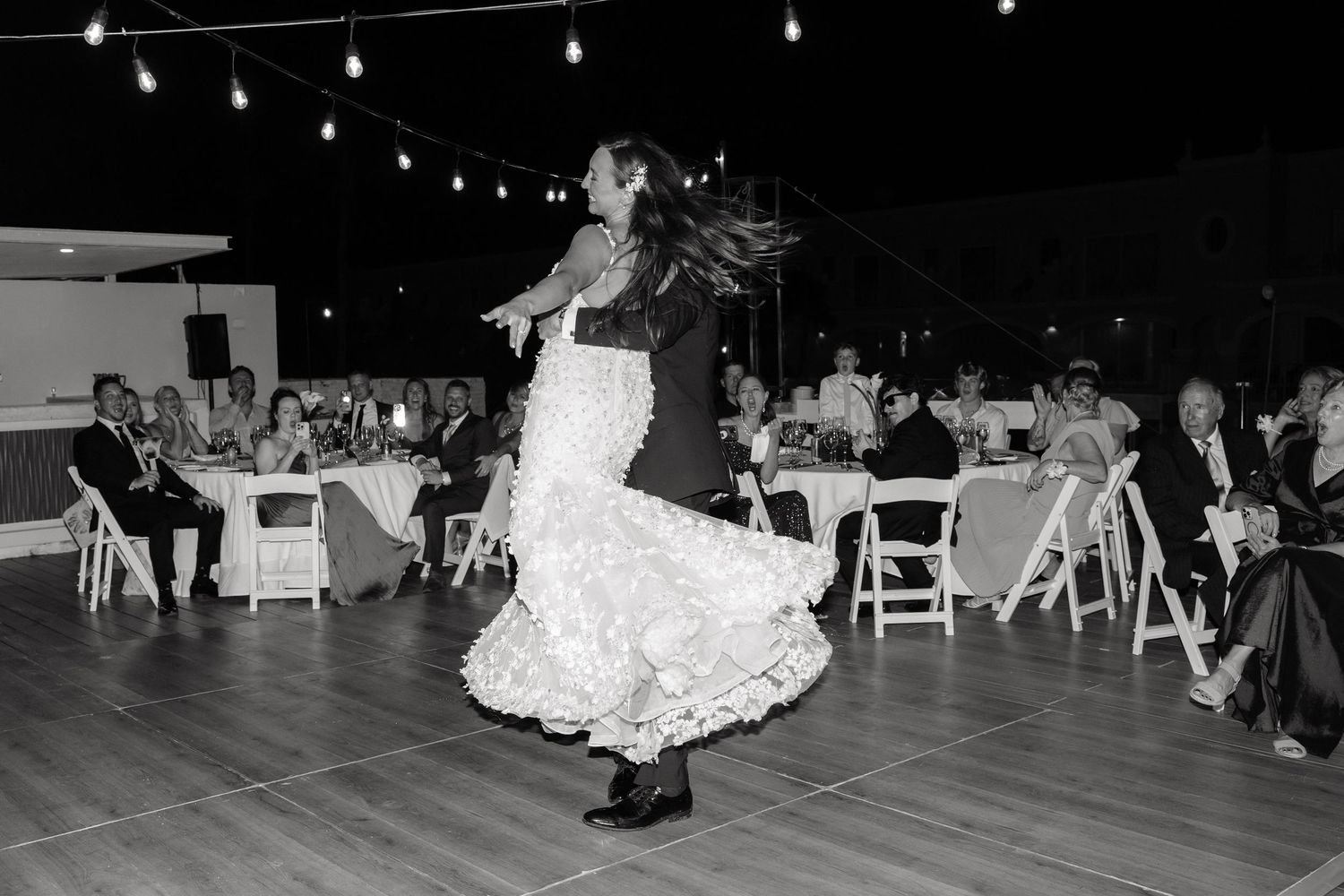 Evening reception under string lights with dancing on outdoor patio.