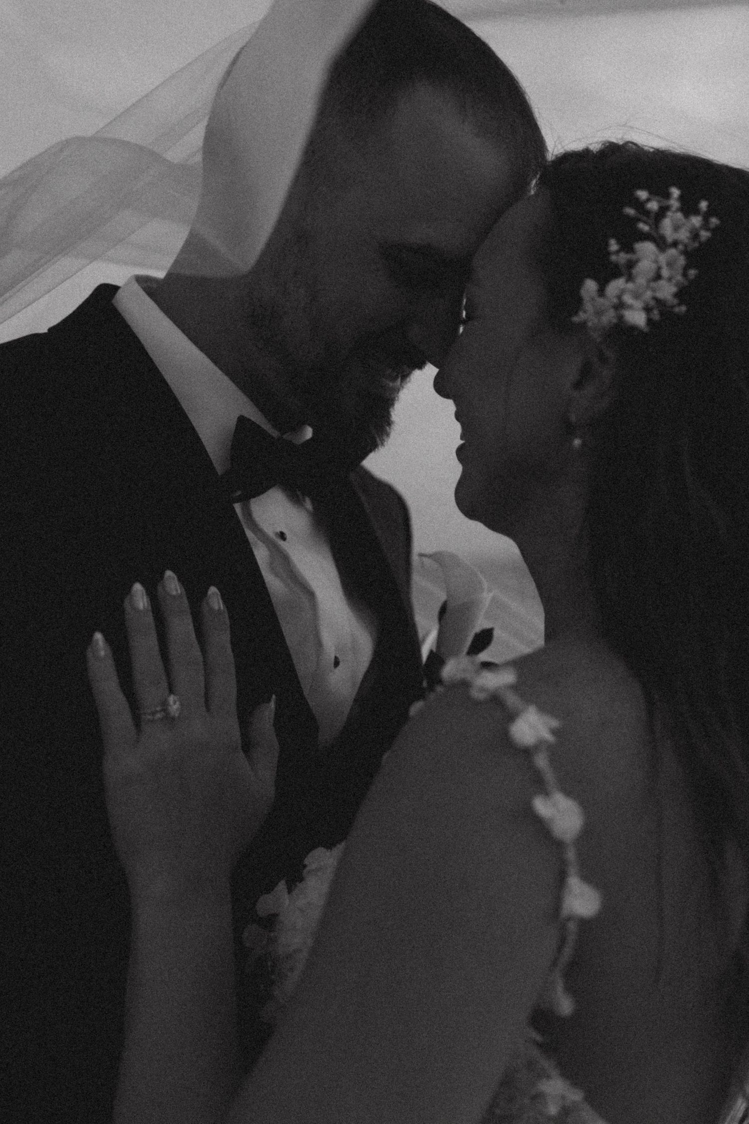 Intimate black and white wedding portraits with dramatic lighting and delicate floral details.