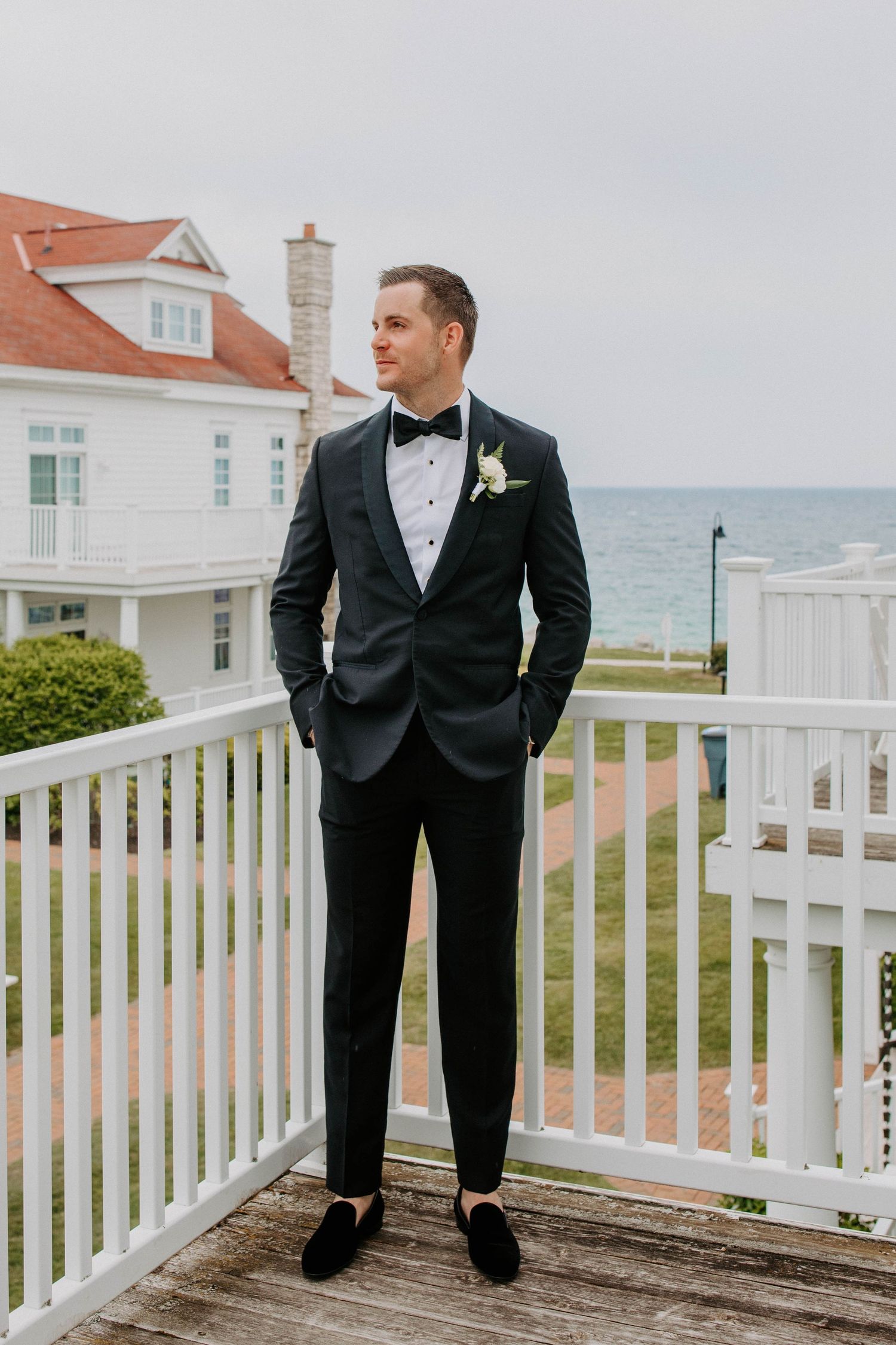 Formal wedding attire against coastal backdrop with white architecture.