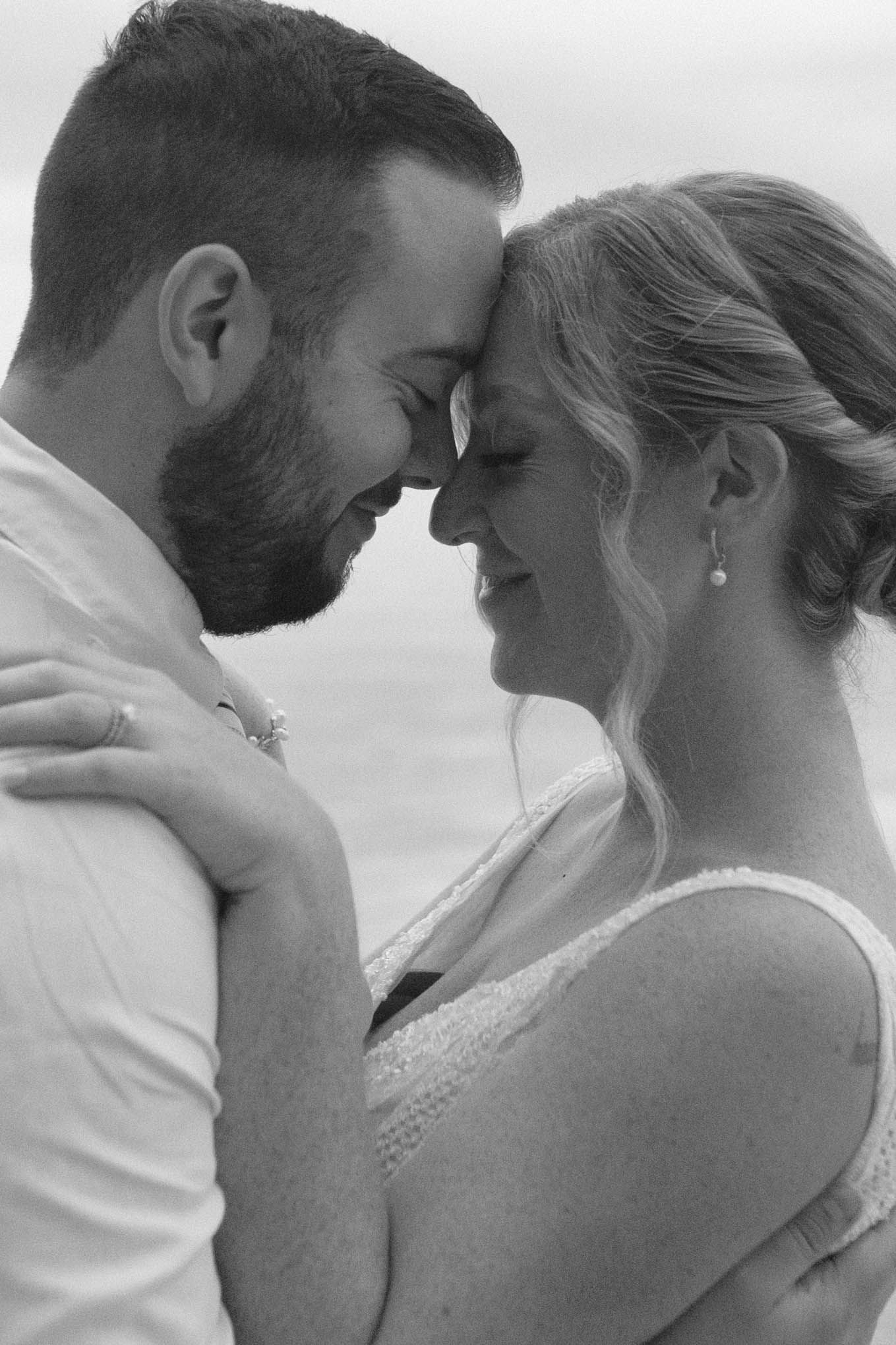 An intimate black and white portrait of a couple sharing a tender moment.