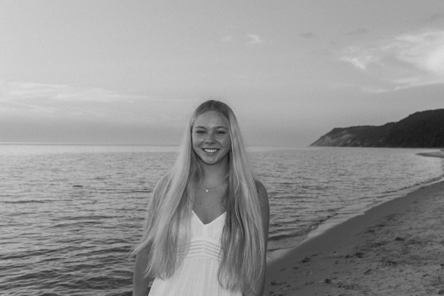 Black and white beach portraits captured during a sunset photoshoot by the water.