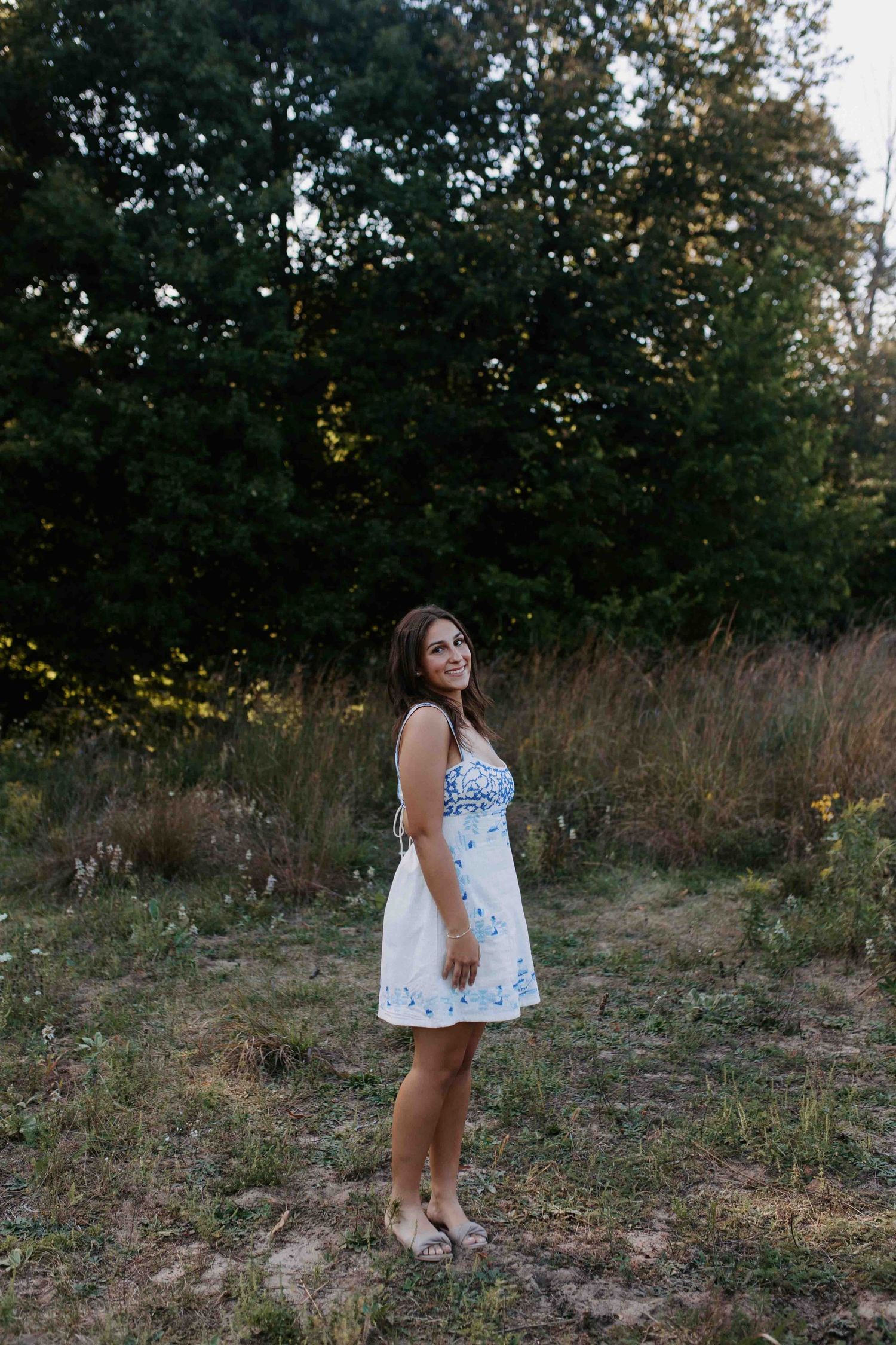 Outdoor fashion photography featuring a white summer dress in a natural setting.