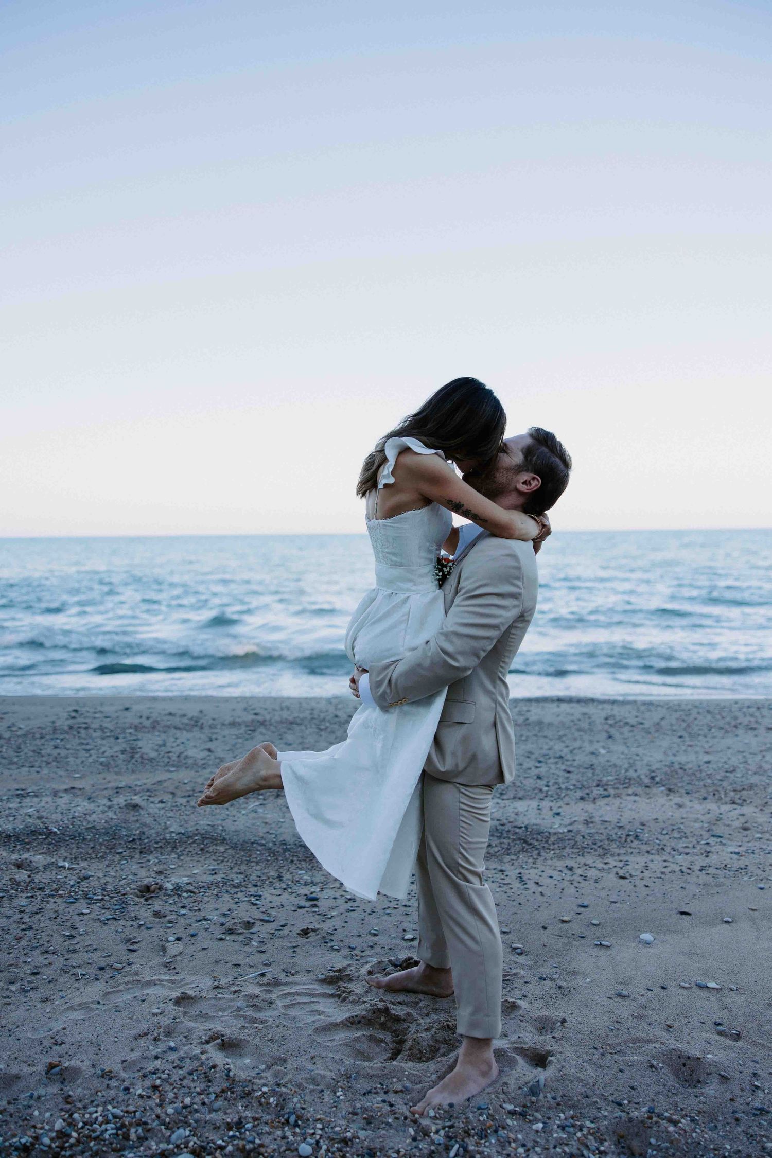 A couple shares romantic moments on a beach at sunset.