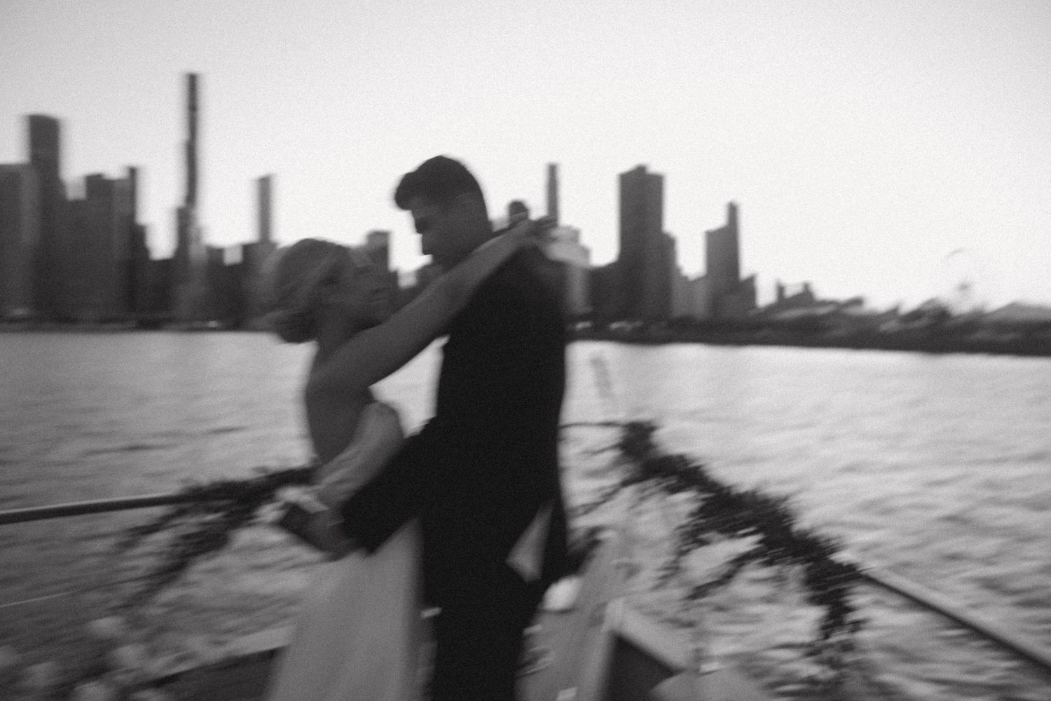 Artistic blurred black and white photo of a couple with city skyline in background.