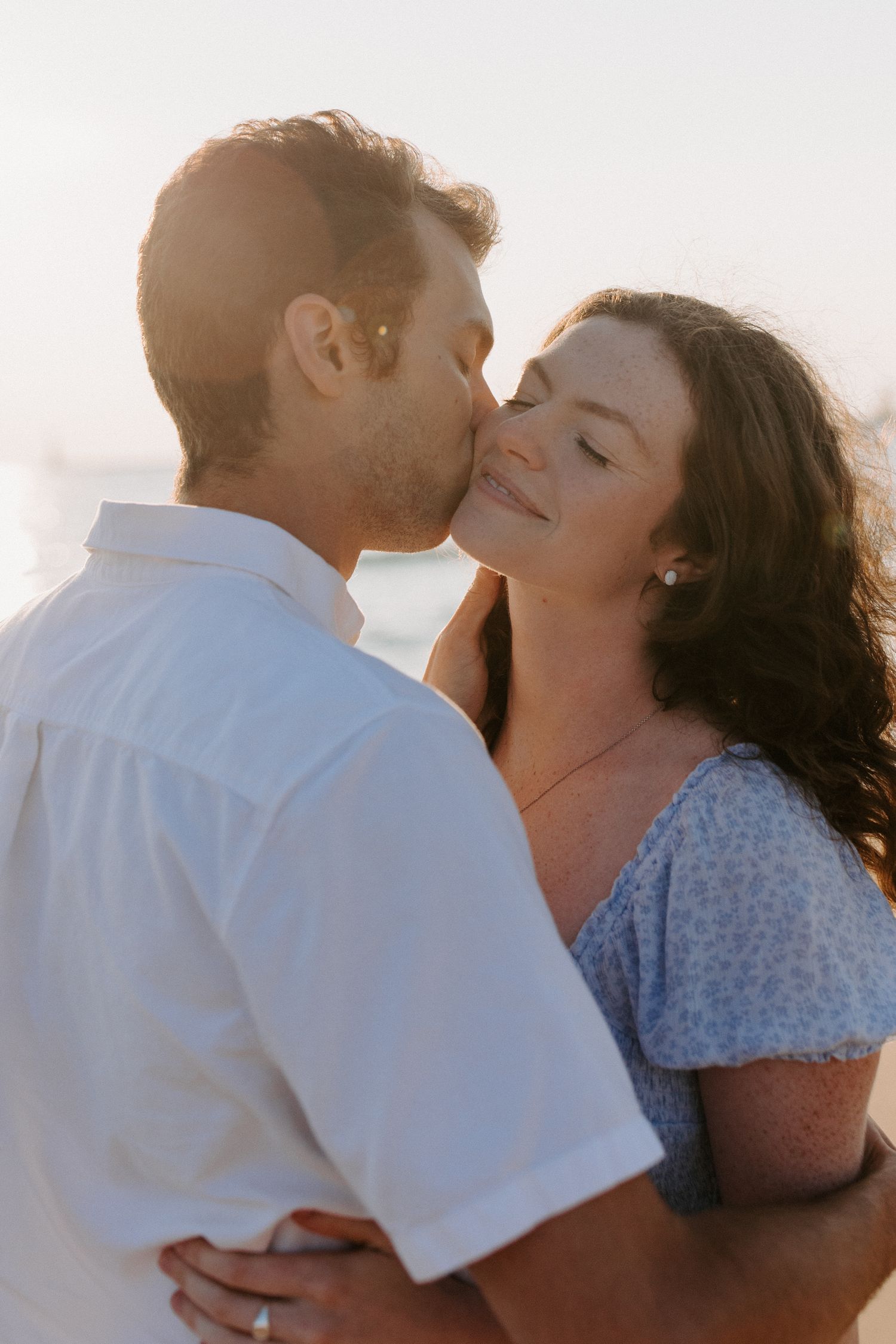 Romantic couple sharing an intimate moment at sunset with warm golden light.