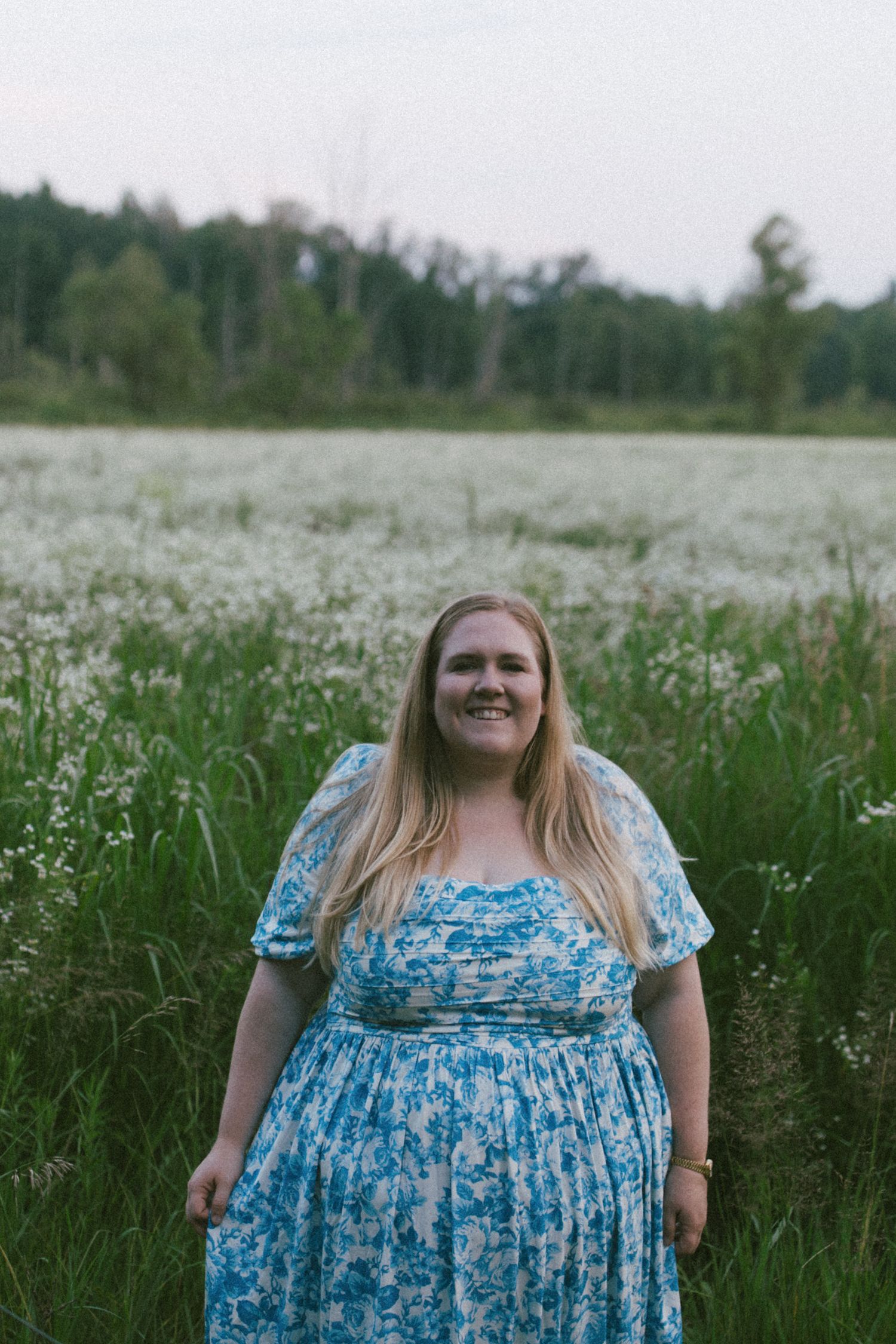 Portrait in a blooming daisy field with person wearing blue floral dress.