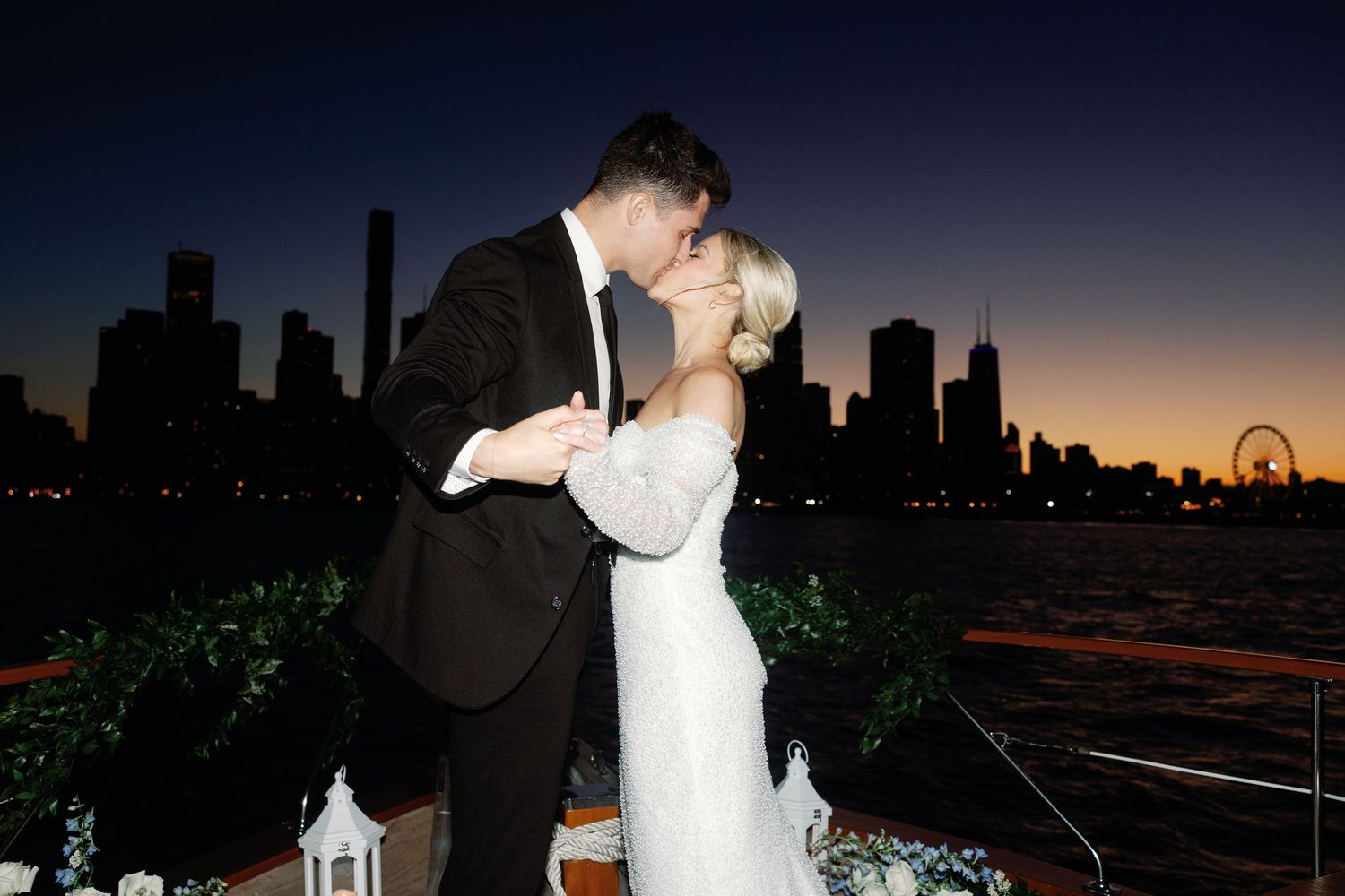 Sunset wedding photos on boat deck with dramatic city silhouette.