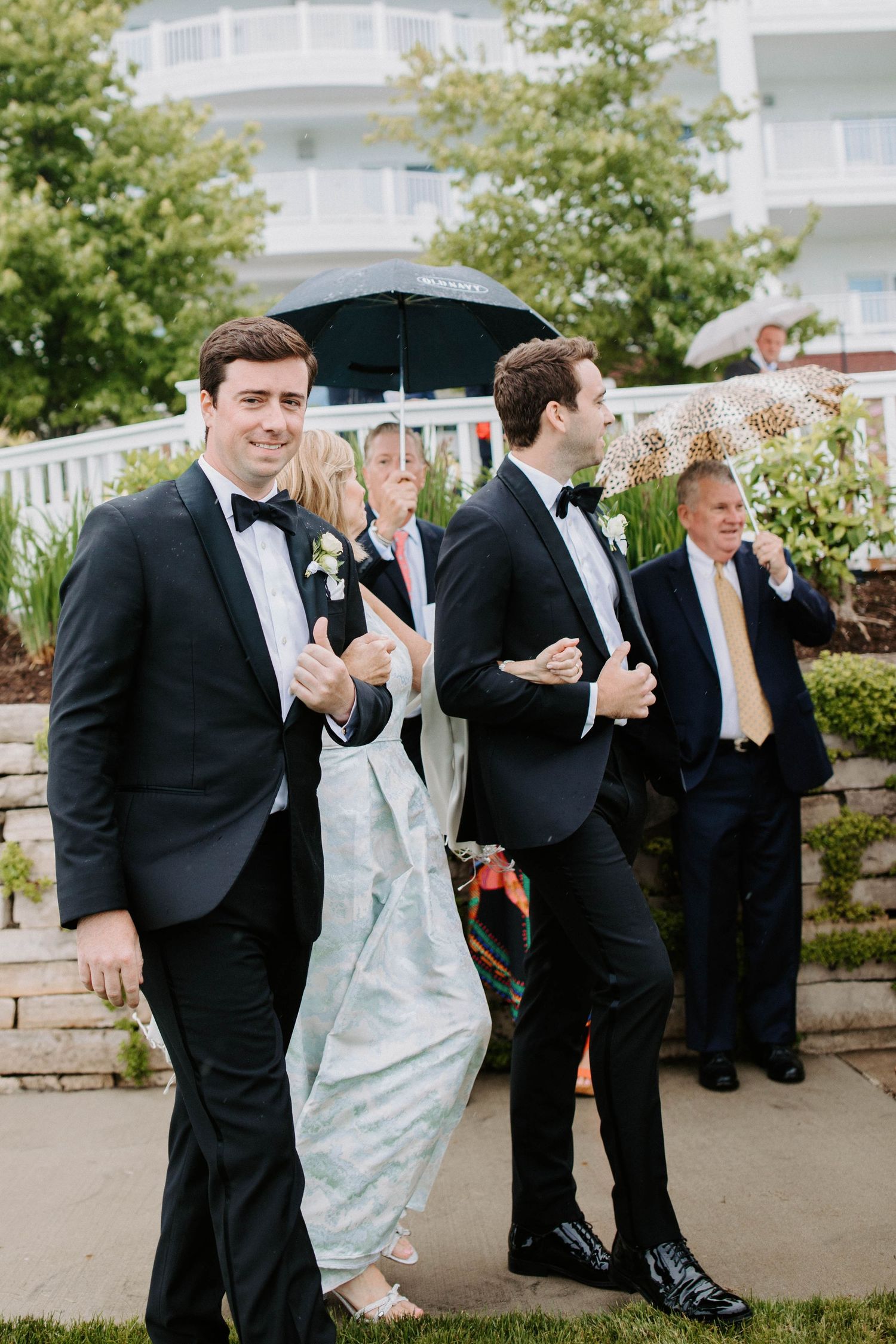 Groomsmen in tuxedos celebrate outdoors during wedding festivities.