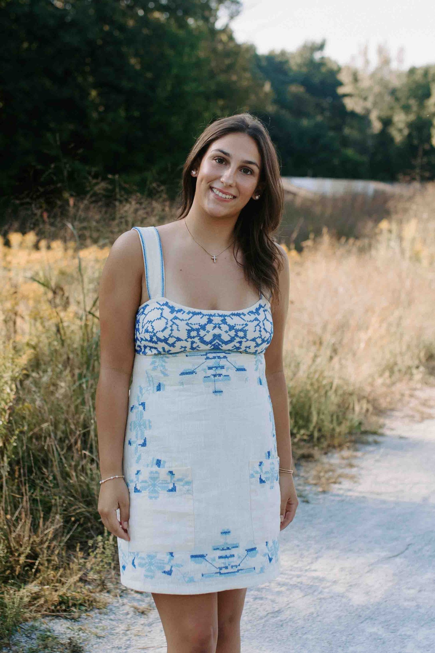Lifestyle portrait on a white gravel path surrounded by golden wildflowers and greenery.