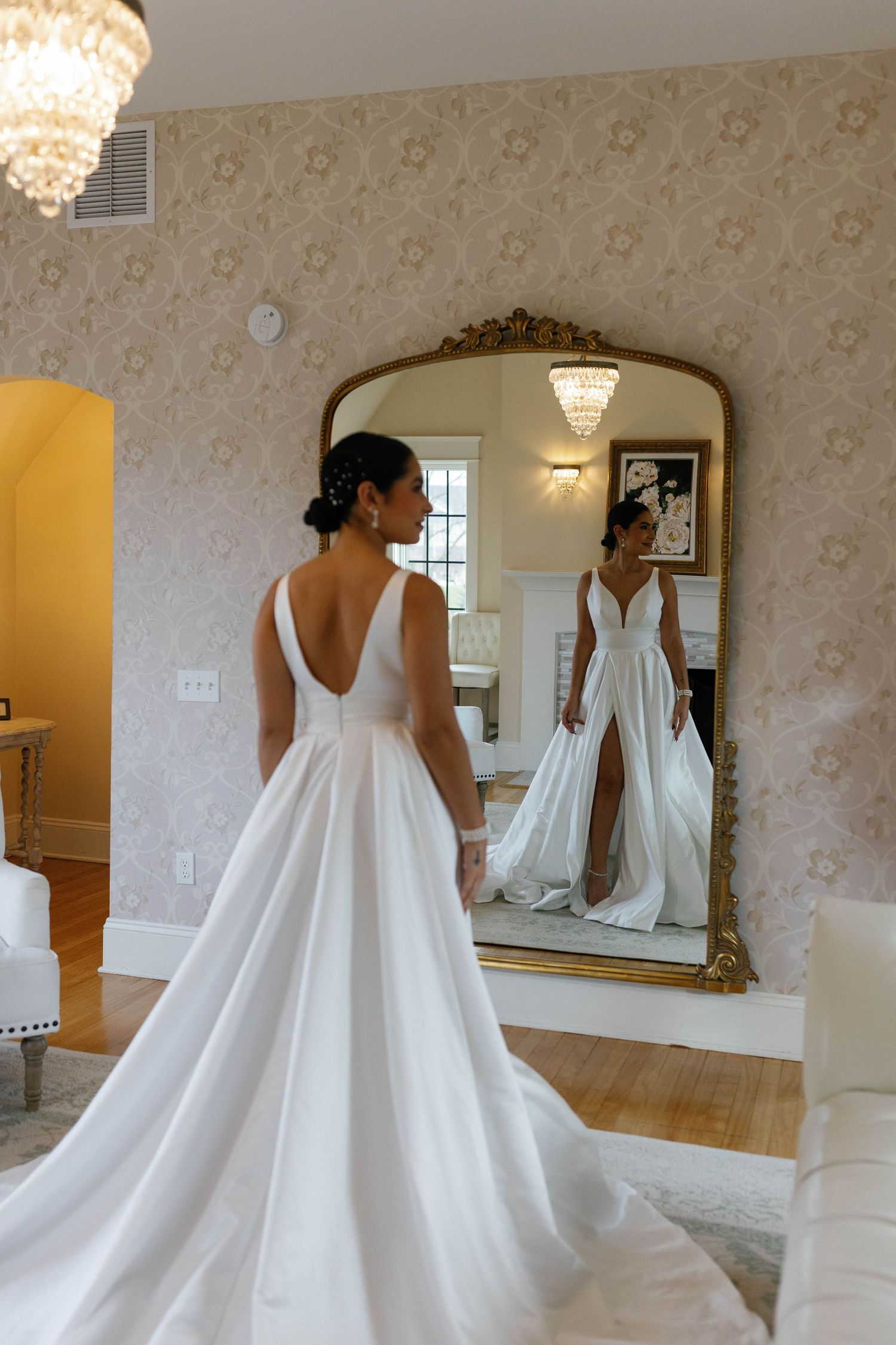 Wedding dress reflection in ornate mirror showing elegant white gown with train.