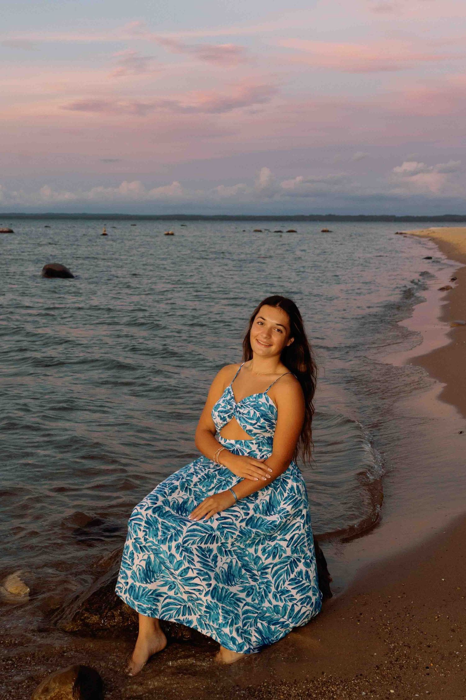 Someone in a blue tropical dress poses gracefully on the beach during magic hour.