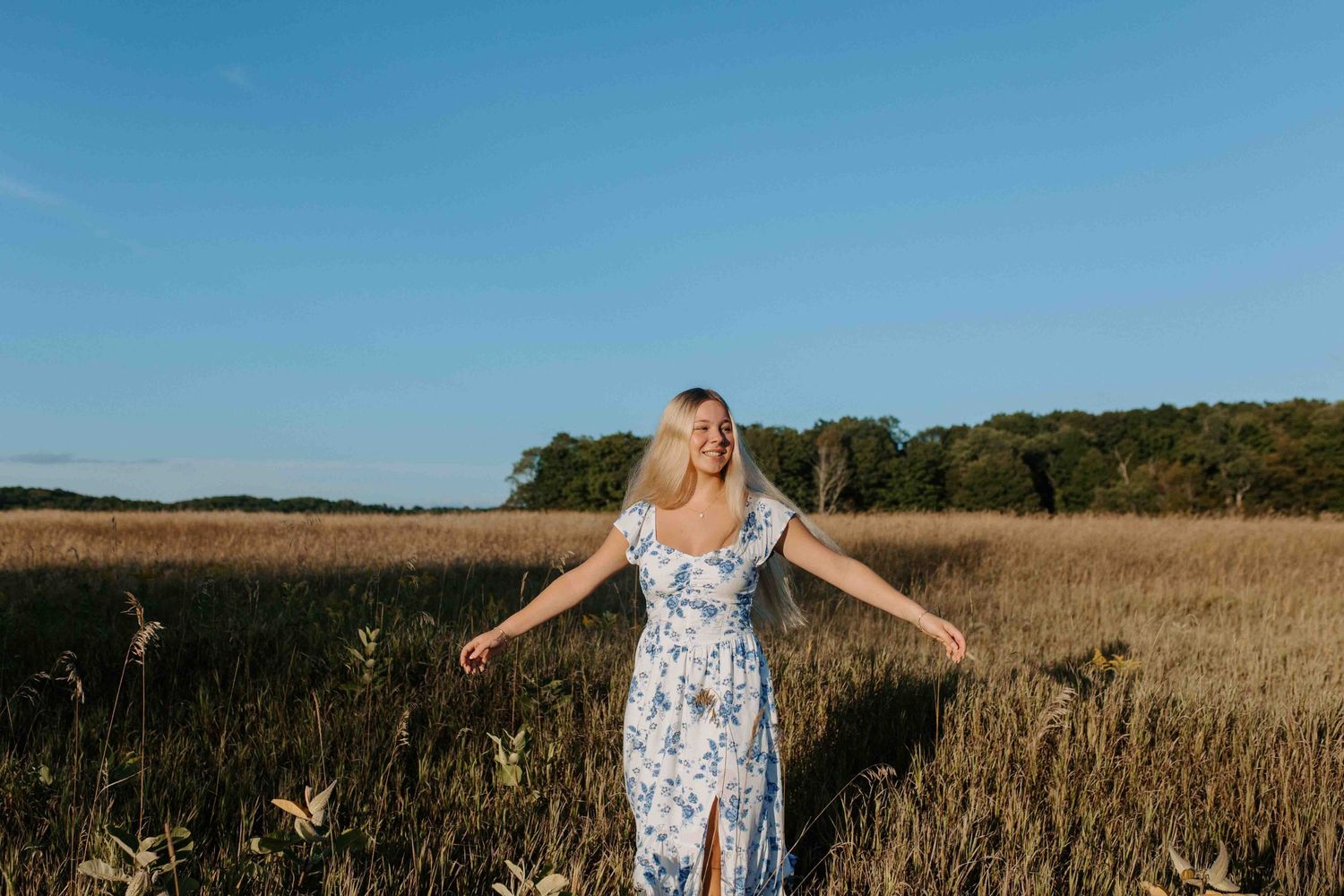 Twirling in a floral dress among wild prairie grass.