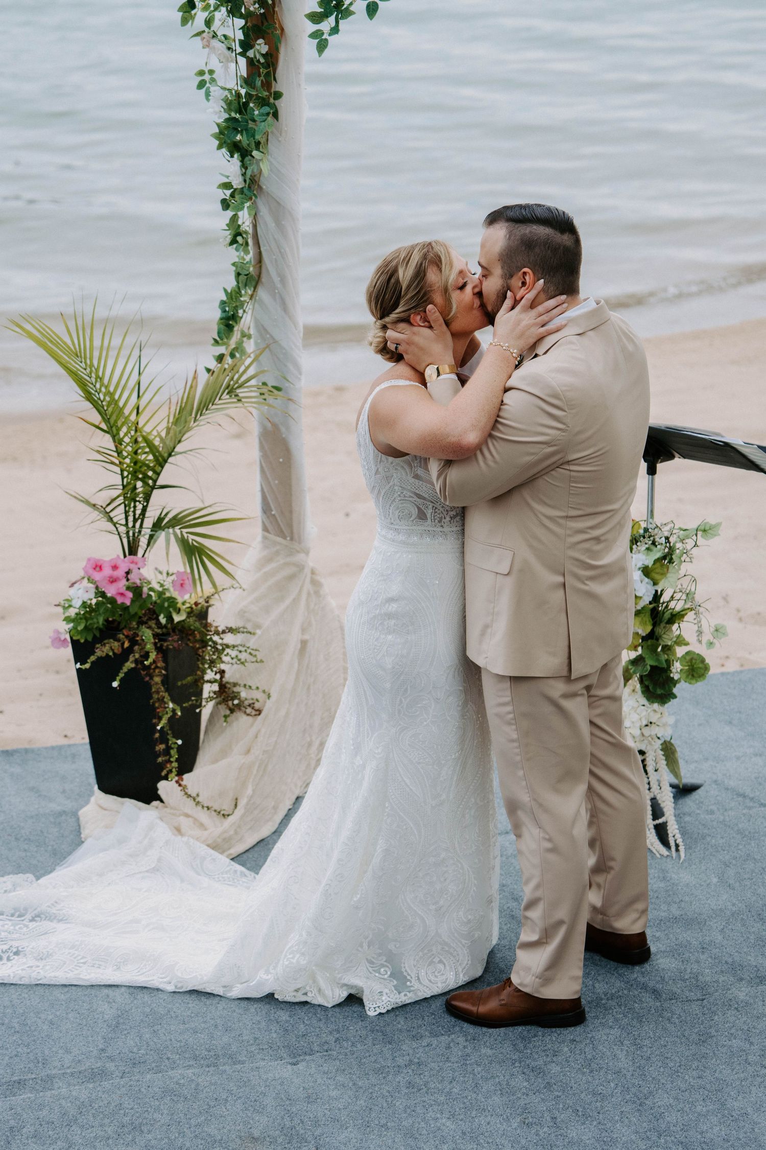 Intimate beachside wedding ceremony with tropical greenery and floral arrangements.