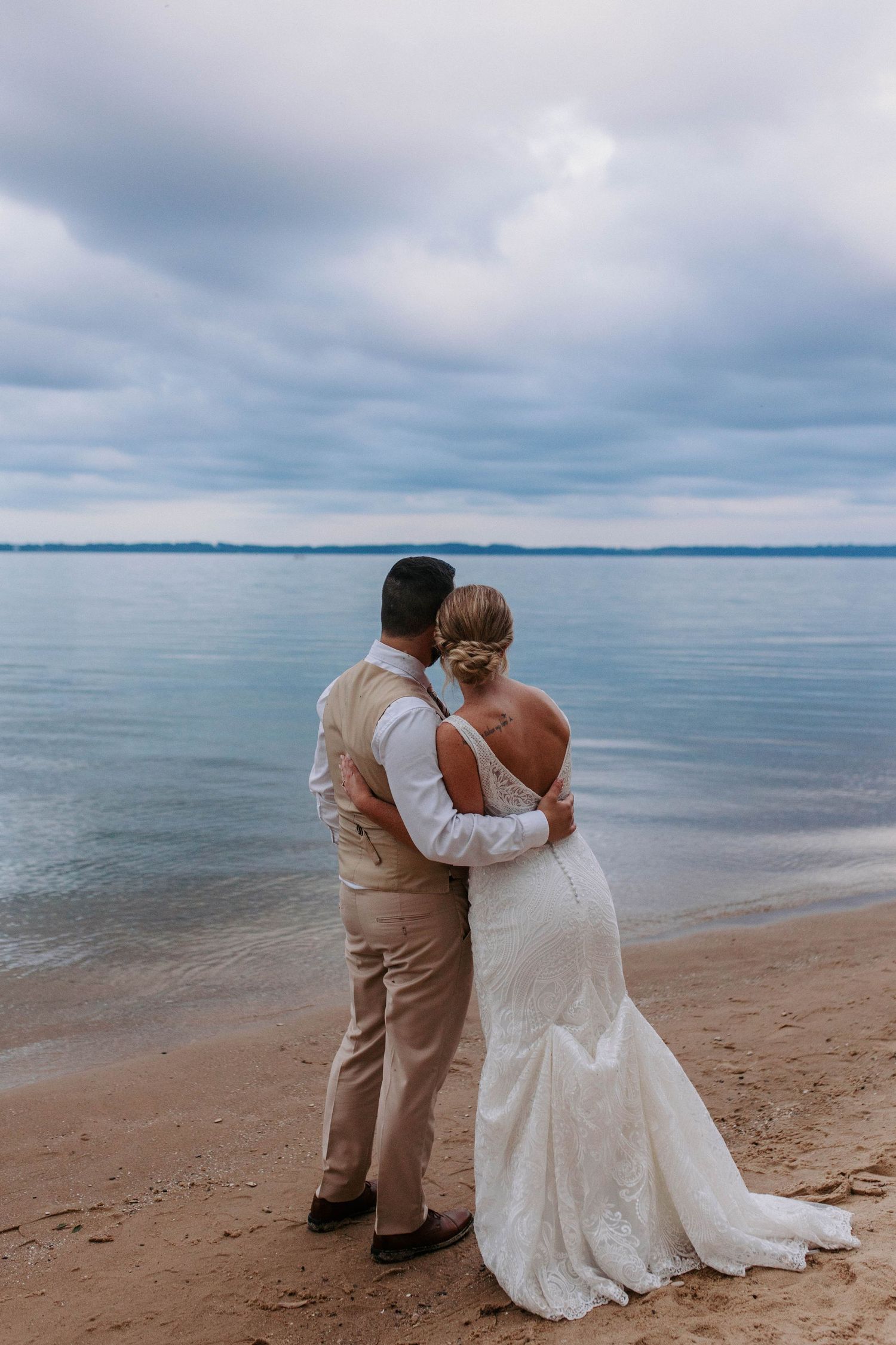 A romantic beachside wedding photo session with couple embracing by the ocean.