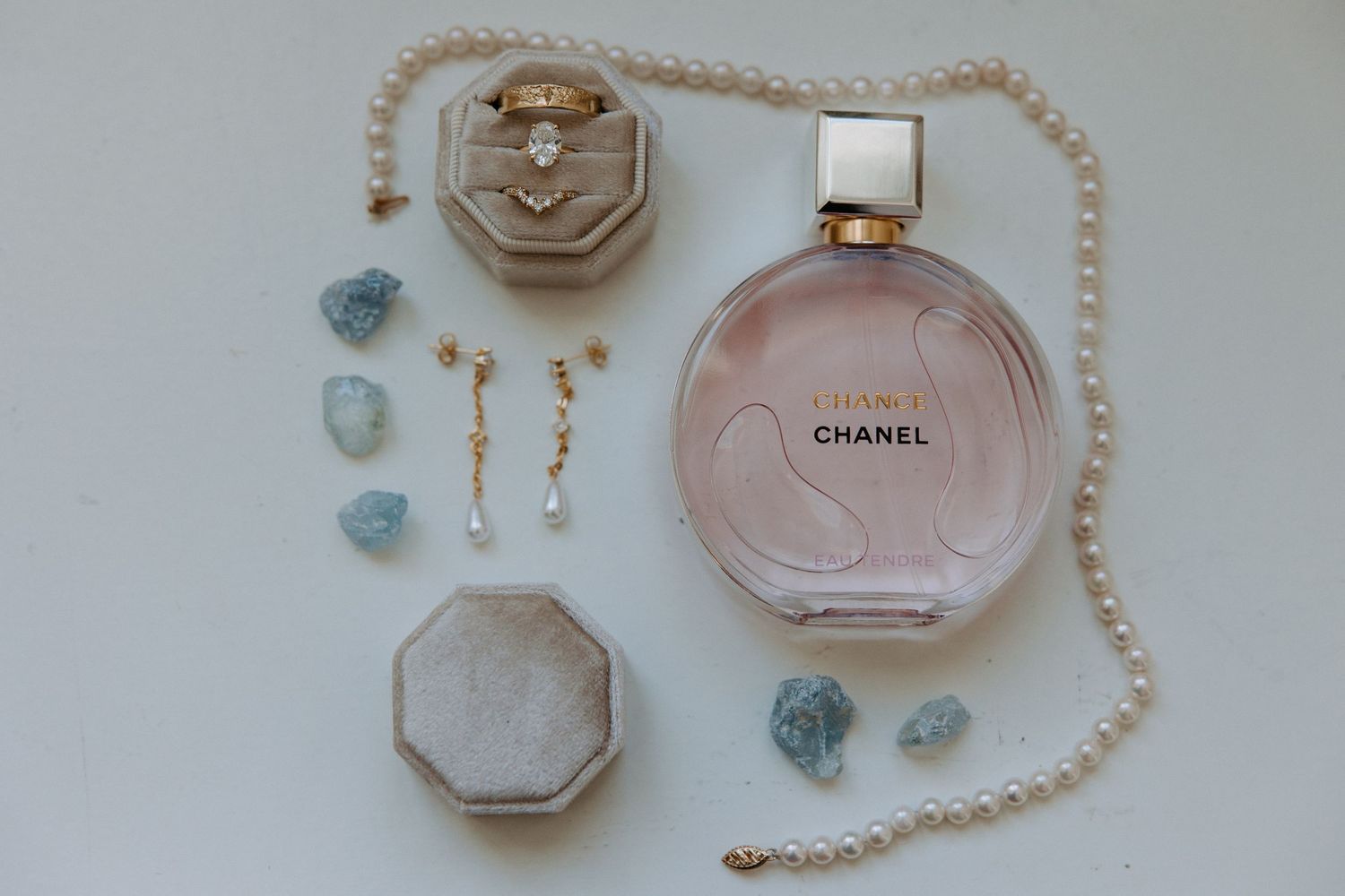 Wedding accessories including perfume bottles, jewelry, and delicate details arranged on a light surface.