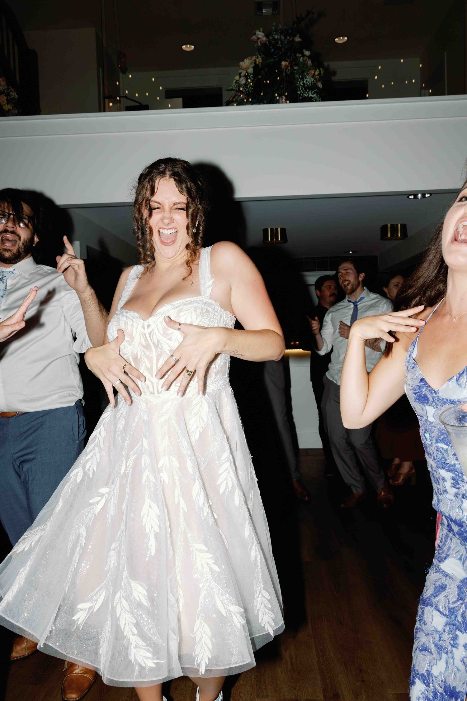 Guests in formal attire dancing and twirling at an indoor wedding reception.