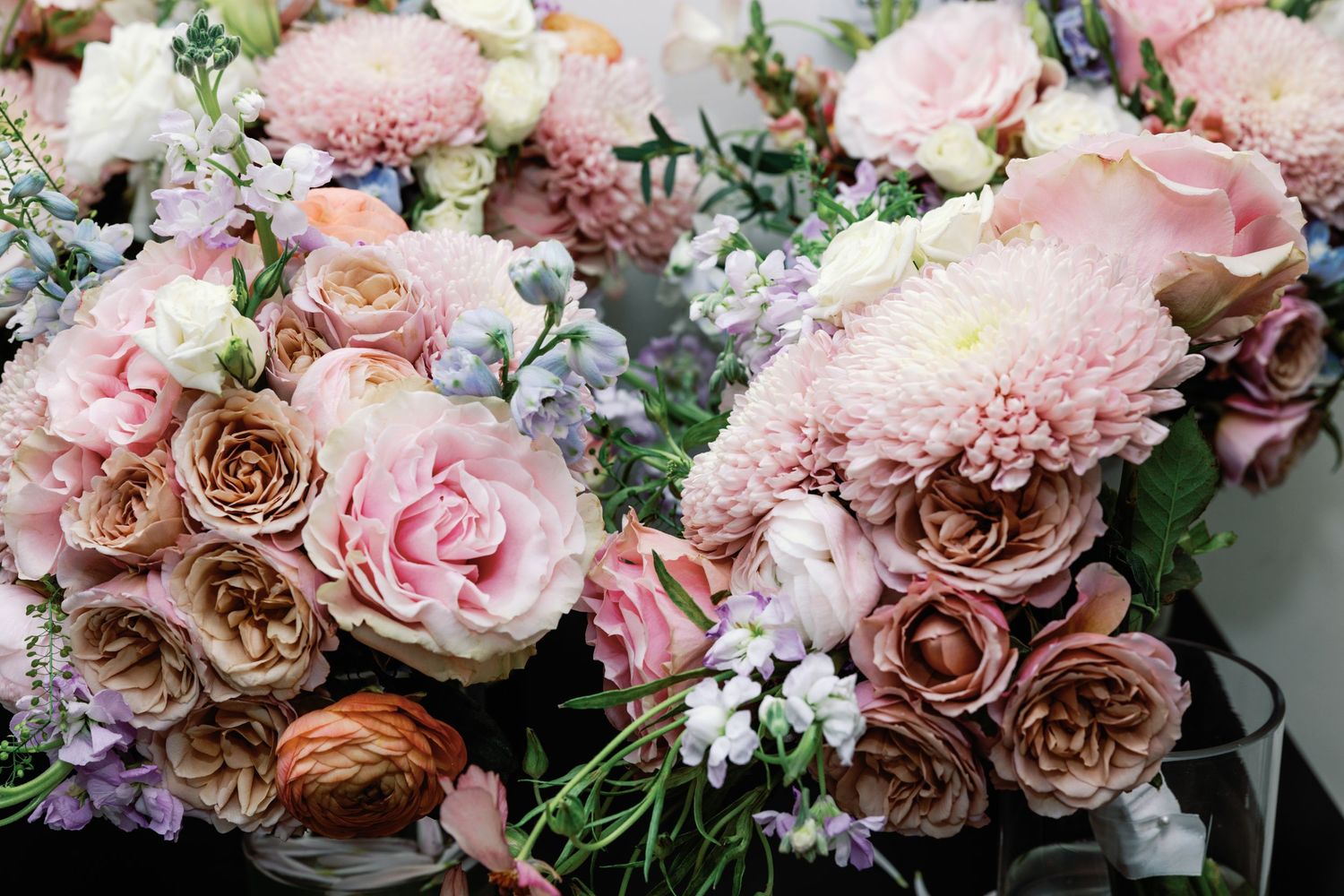Romantic arrangement of pink and mauve roses with mixed flowers for wedding decor.