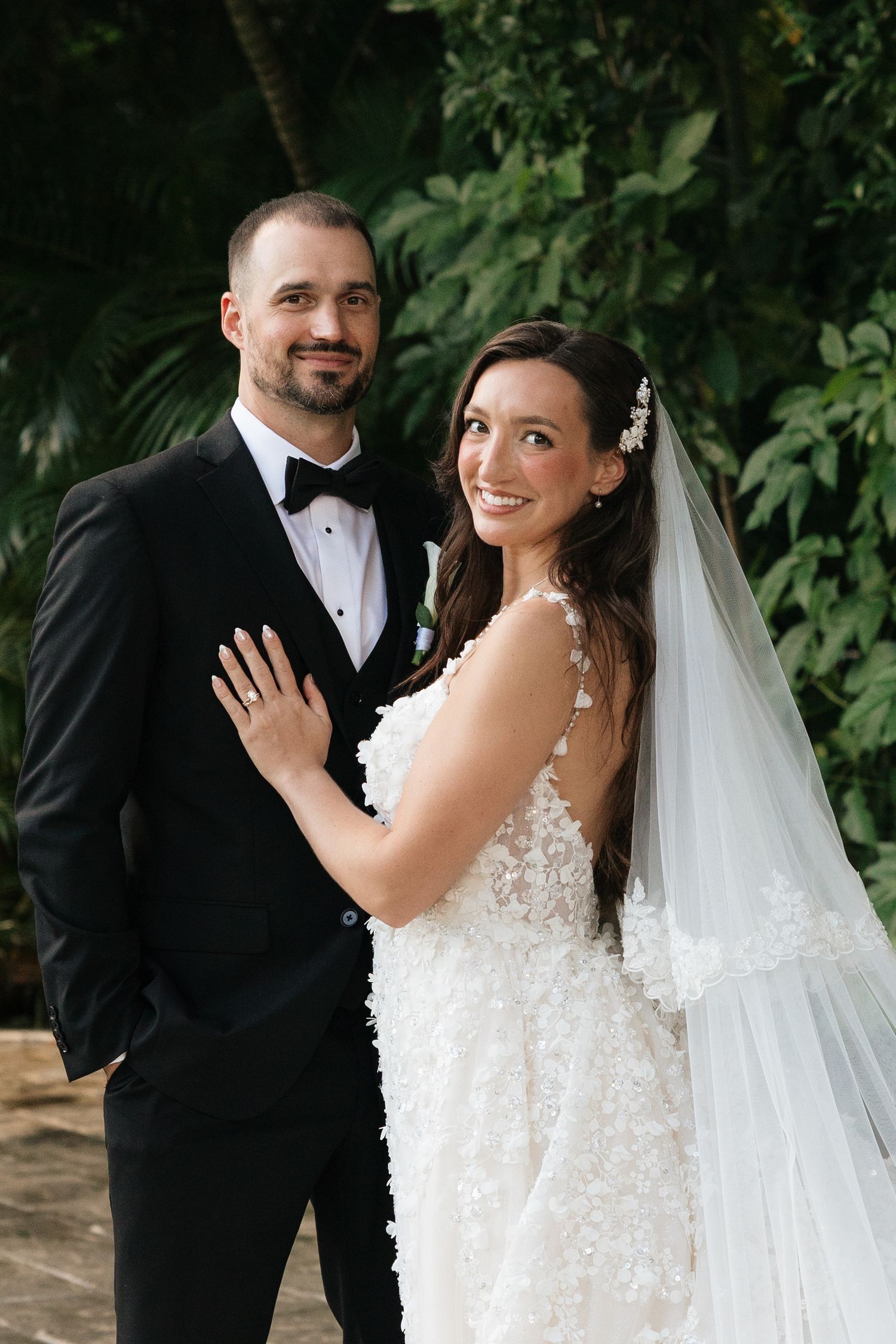 Romantic wedding portraits on stone pathway with lush greenery backdrop.