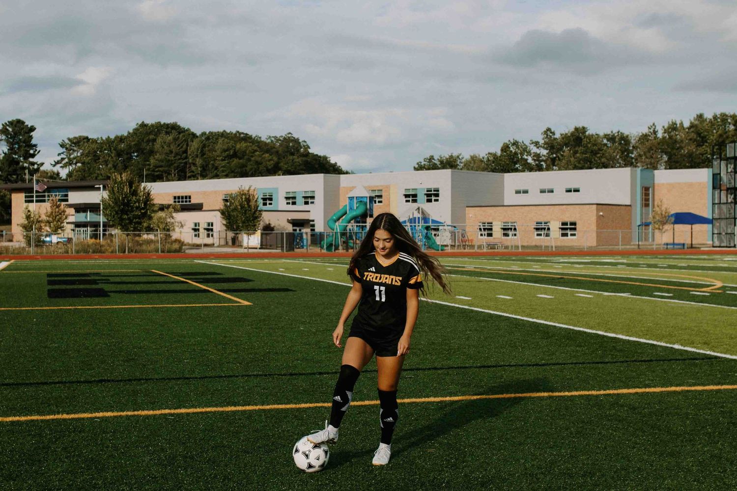 Soccer player dribbles ball during practice on turf field.