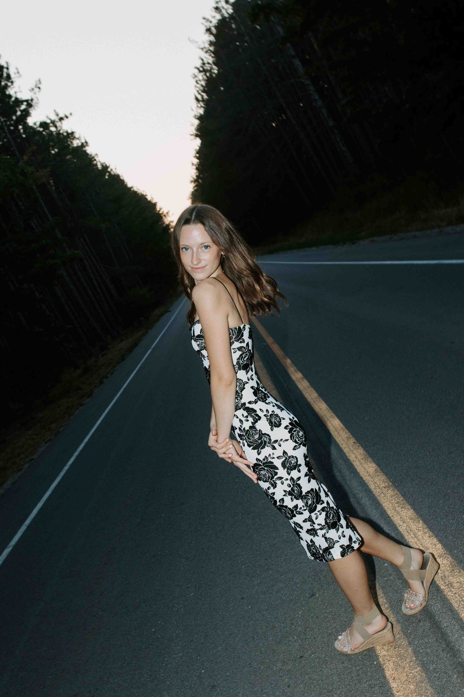 Dynamic poses on an asphalt road at dusk in a floral print dress.
