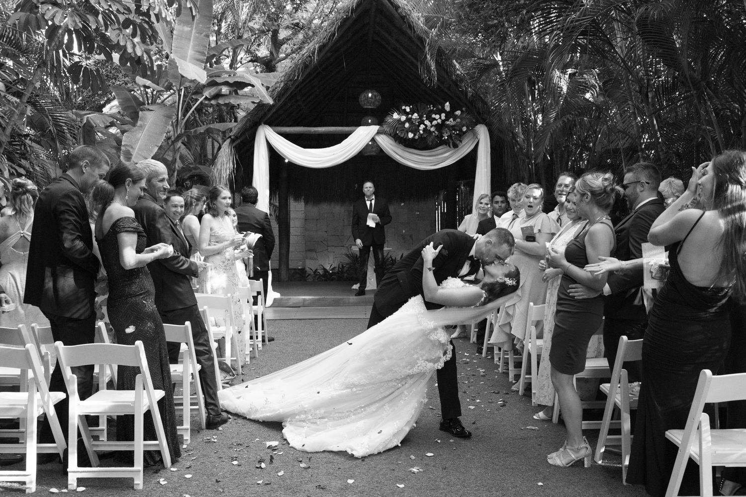 Black and white panorama of a wedding ceremony with guests seated outdoors.