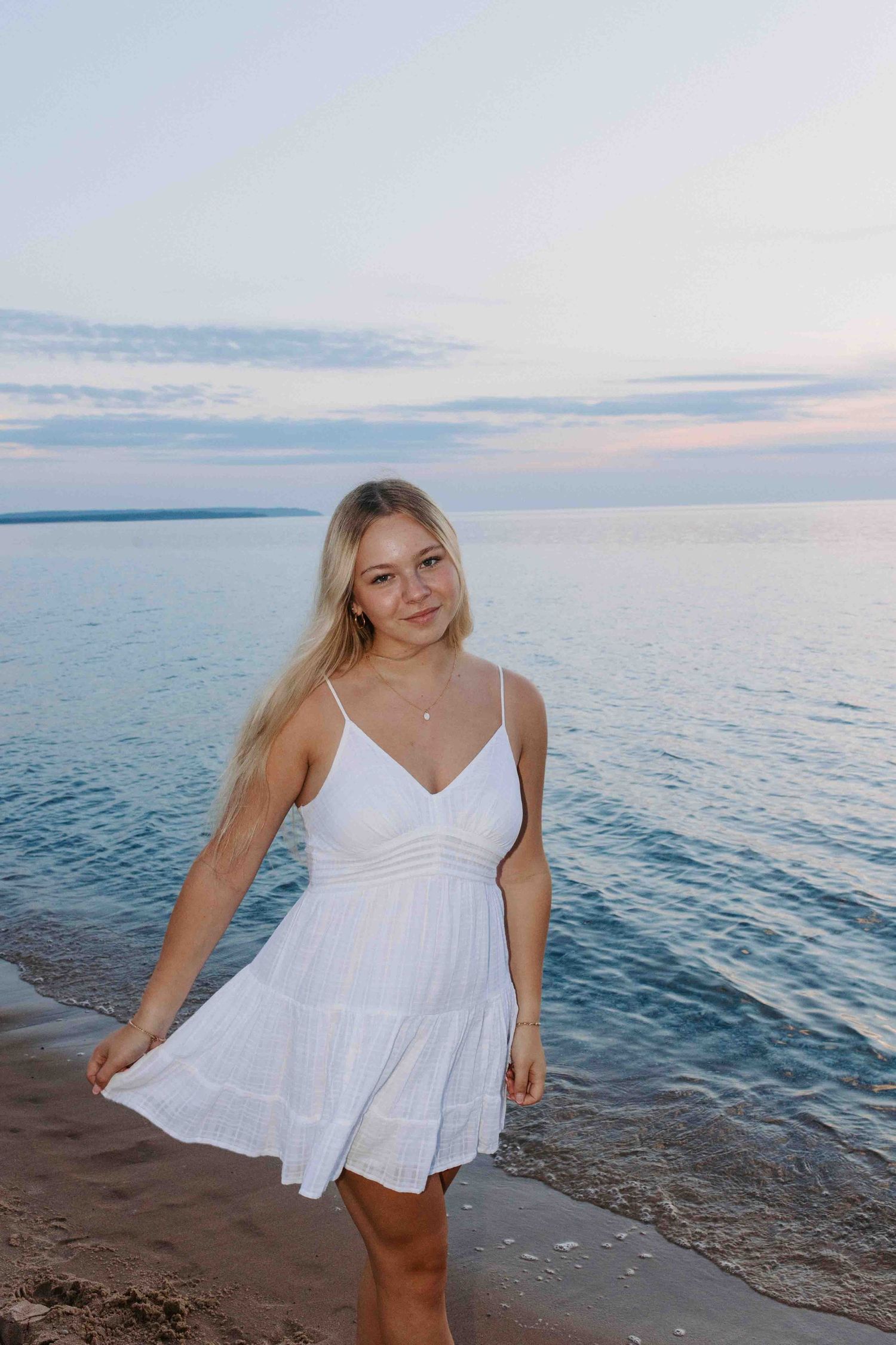 Sunset beach portraits with someone wearing a white summer dress near the ocean waves.