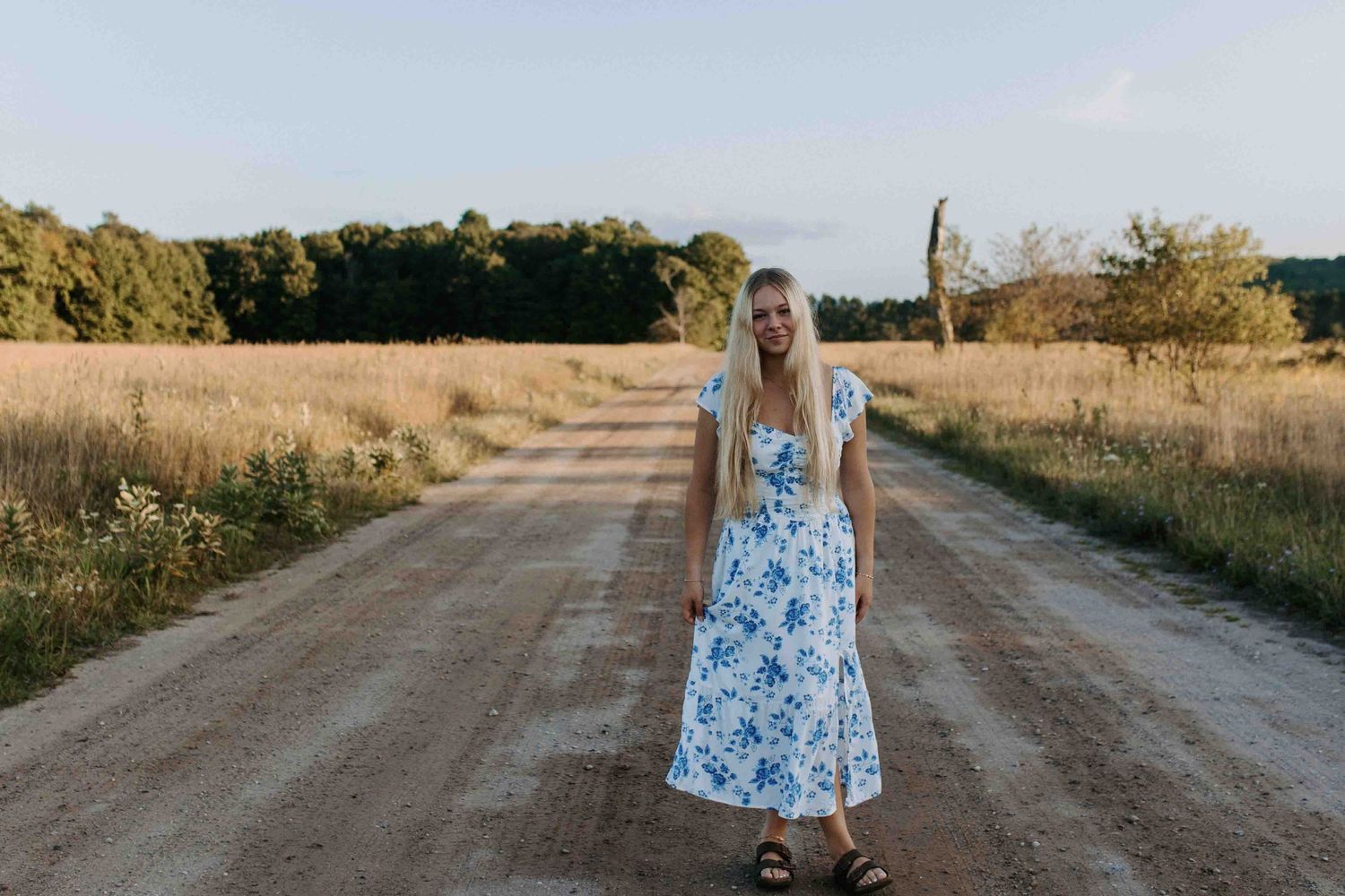 Walking down a rural dirt path surrounded by tall grass.