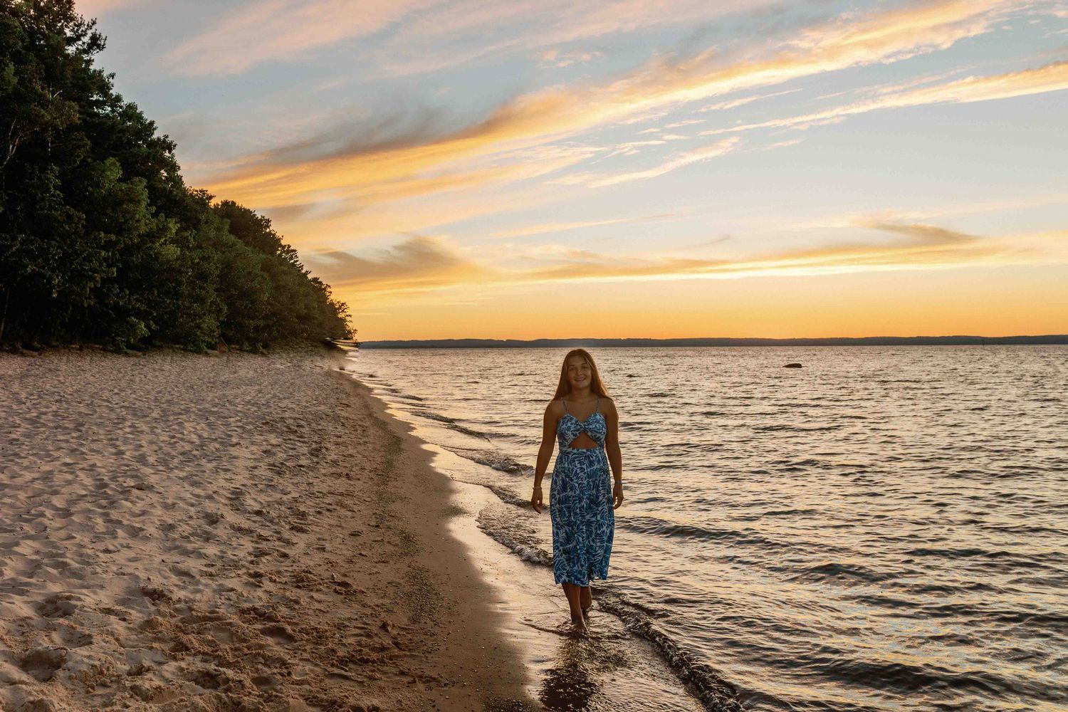 Dramatic orange sky illuminates a peaceful beach scene at sunset.