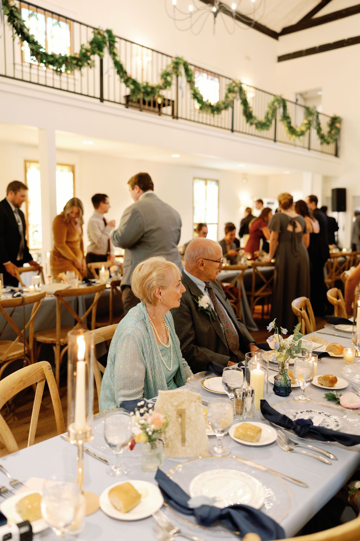Wedding reception dining room with elegant table settings and holiday garland decorations.