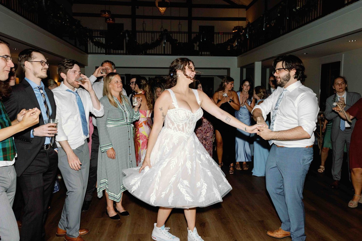 Wedding party and guests dancing enthusiastically on a wooden dance floor.