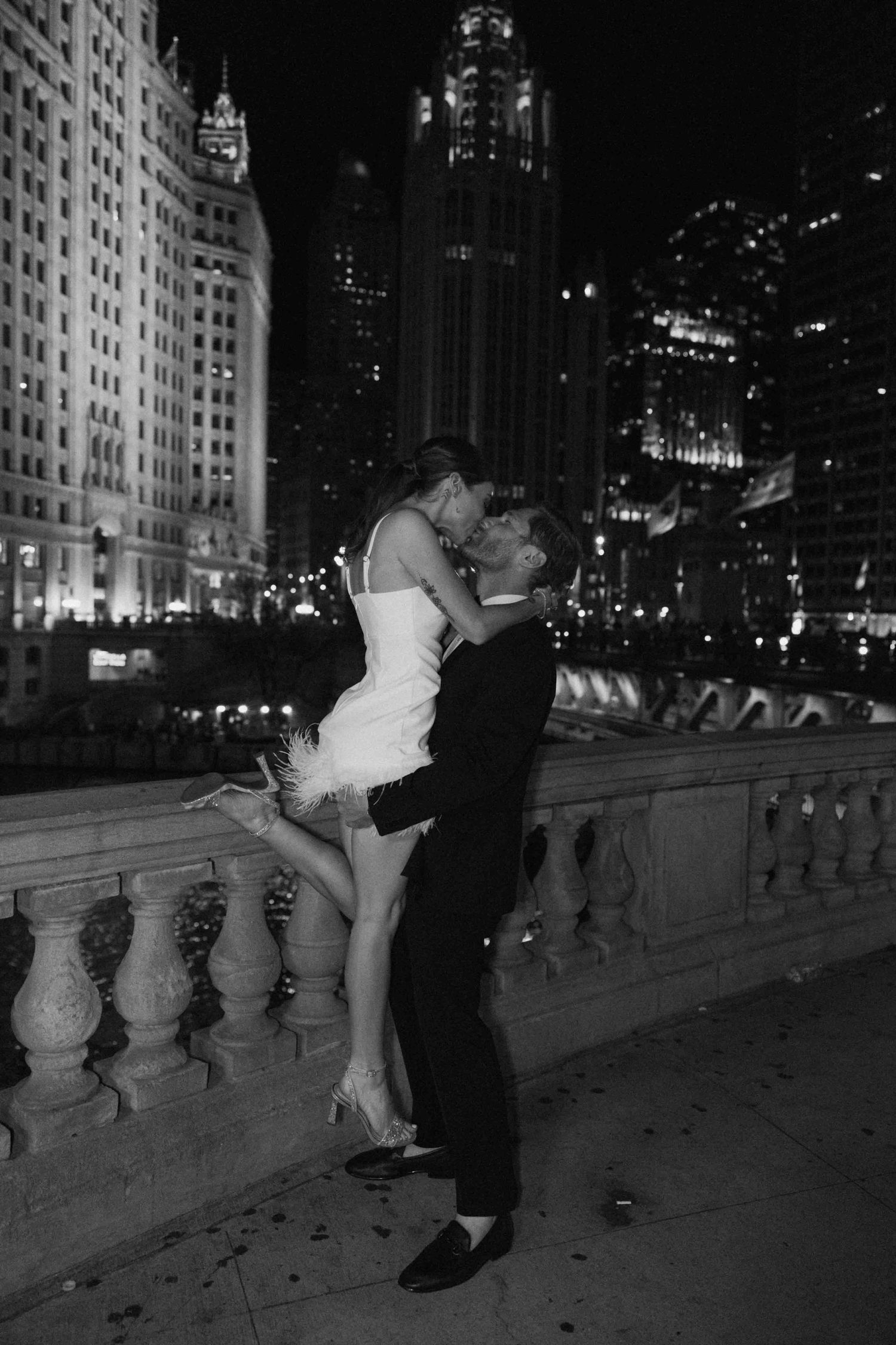 A romantic nighttime dance sequence along a stone balustrade with city lights in the background.
