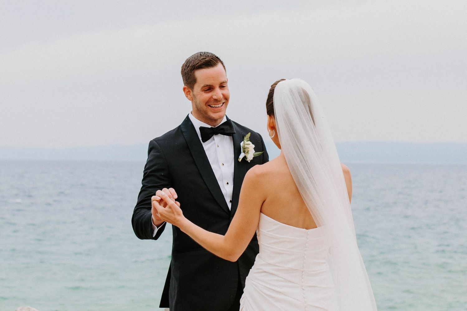 A couple shares their first look moment by the ocean on their wedding day.