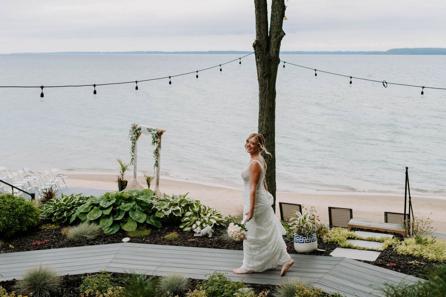 String lights hang over an elegant waterfront wedding venue at dusk.
