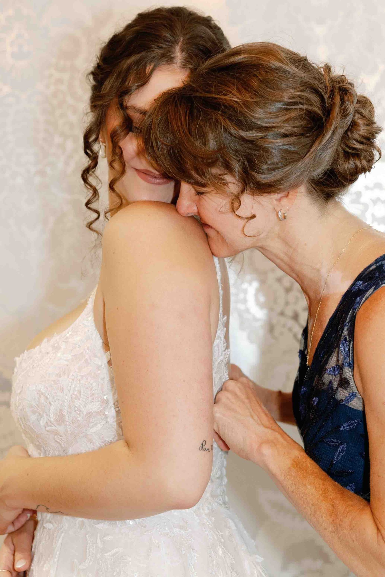 Someone adjusting the back details of an elegant white wedding dress.