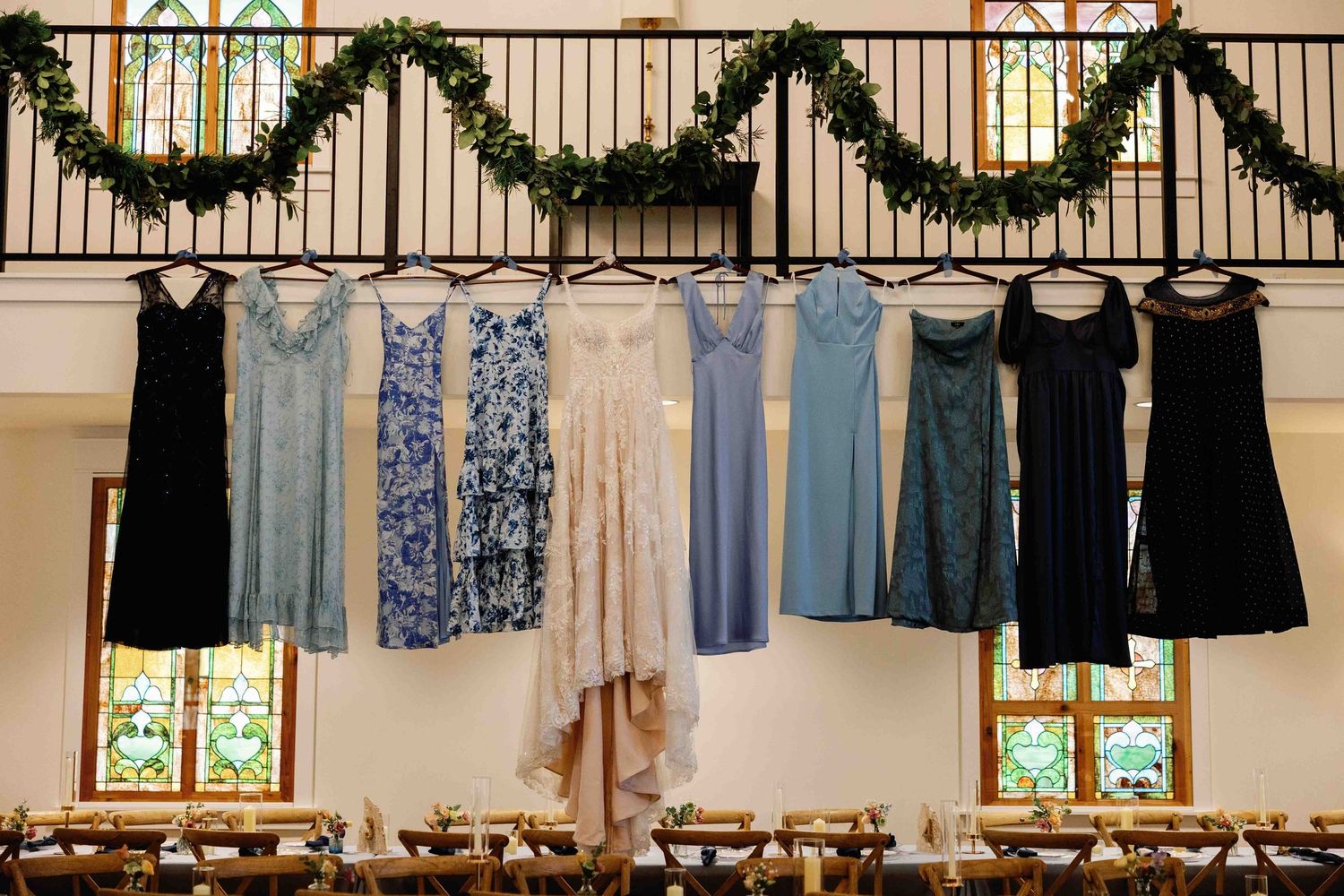 Wedding venue decorated with elegant greenery garlands and hanging lights along a railing.