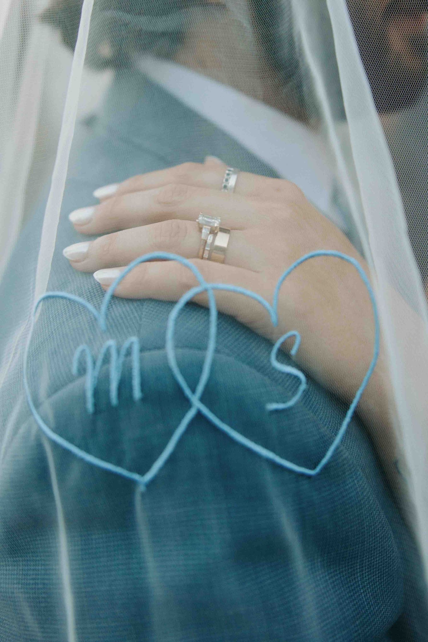 Wedding ring displayed through delicate veil fabric with artistic blur effect.