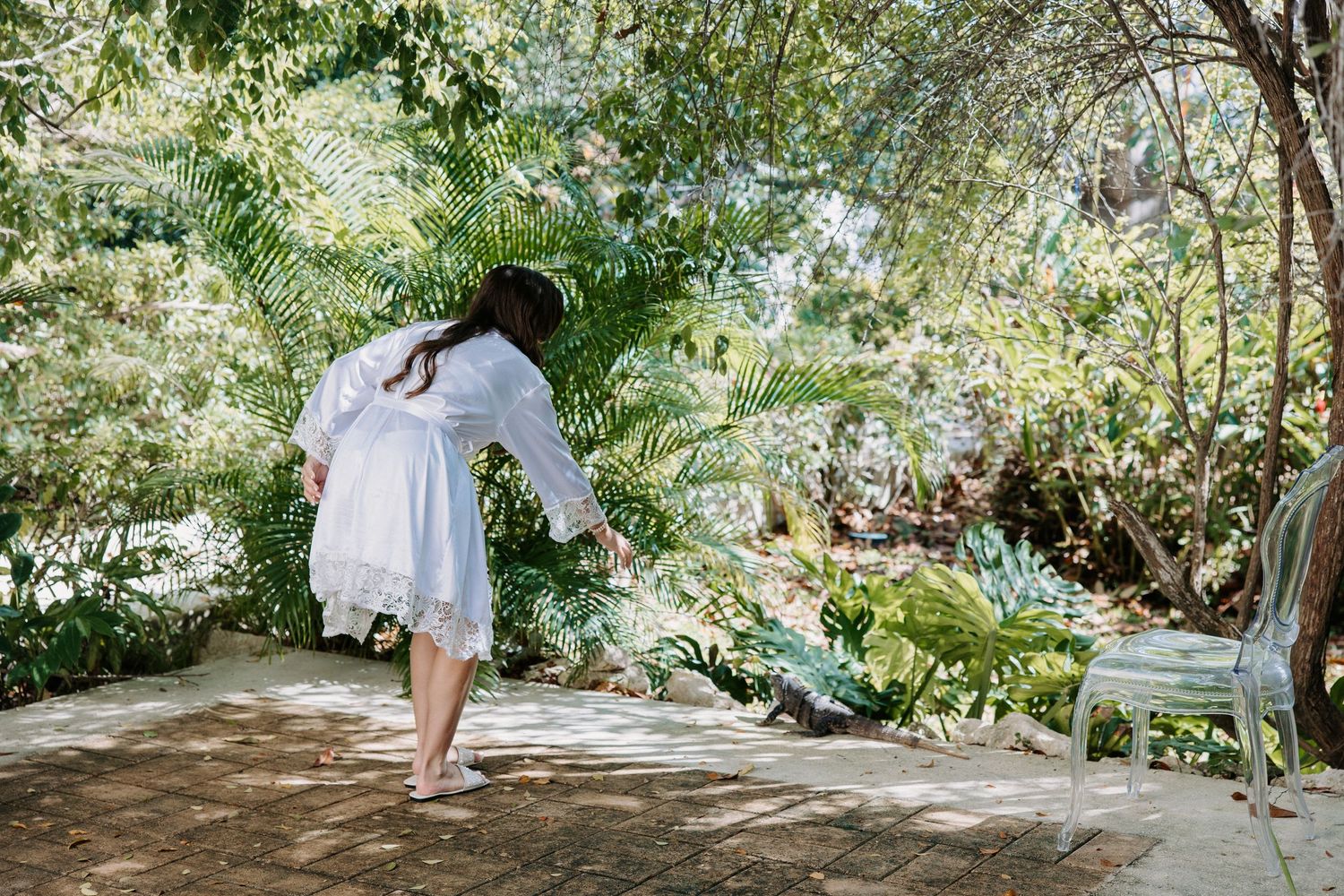 Wedding party members in white outfits walking through a garden path.