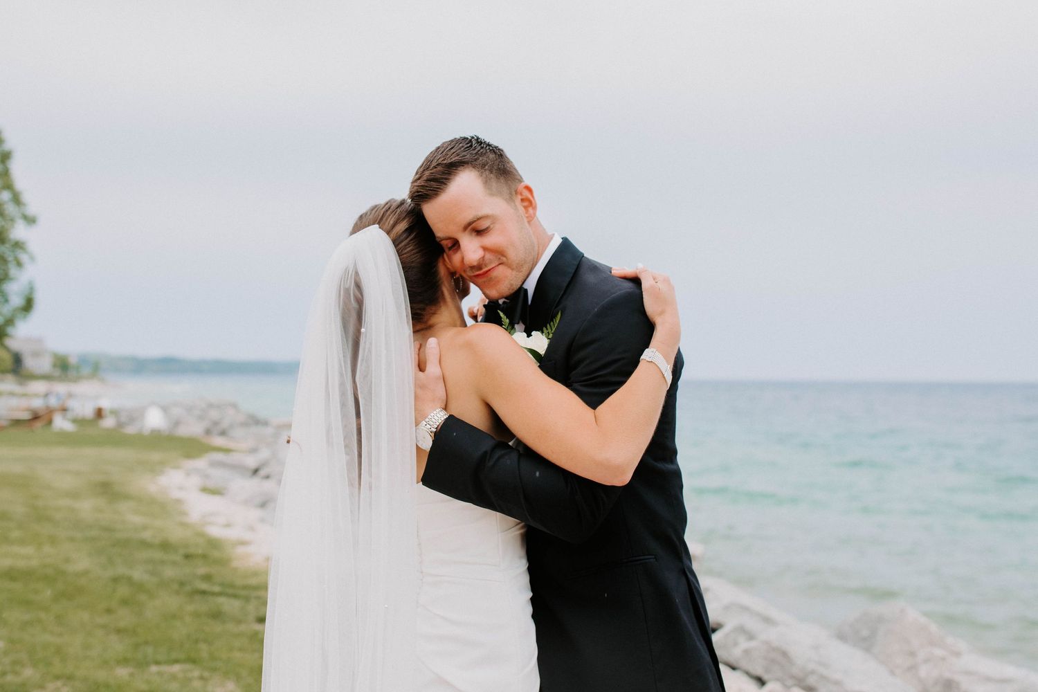 Emotional wedding moment captured against serene oceanfront setting.