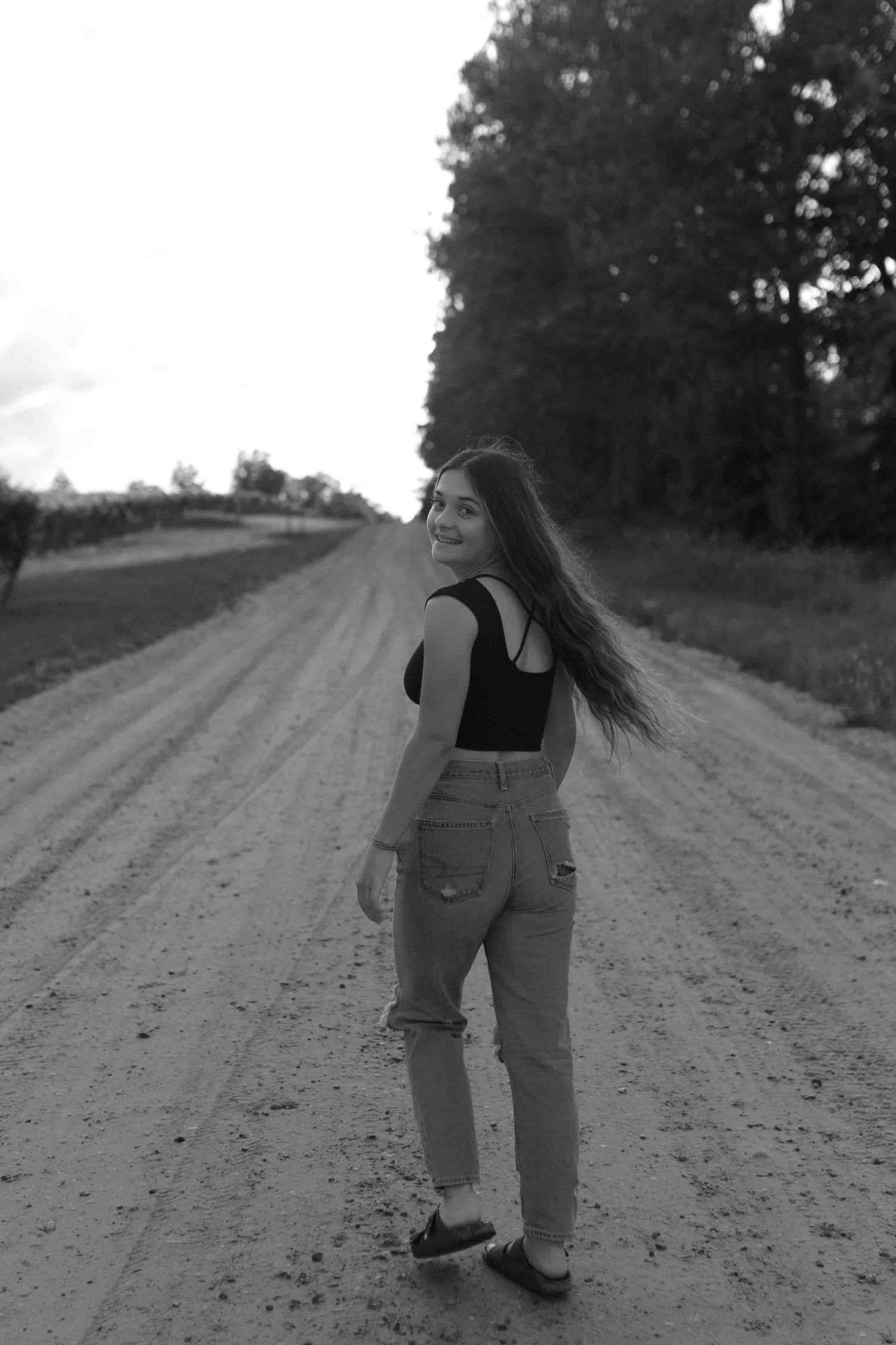 Black and white photo of two people walking down a country dirt road.