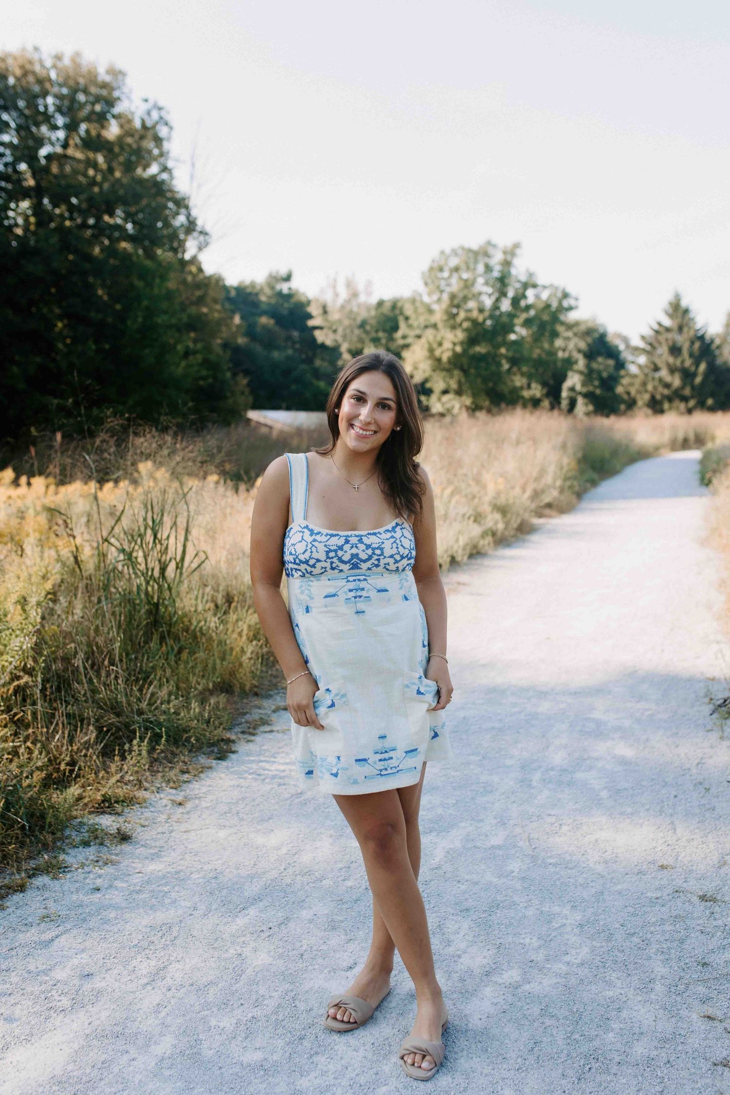 Summer fashion photography on a white gravel path with natural golden grass backdrop.