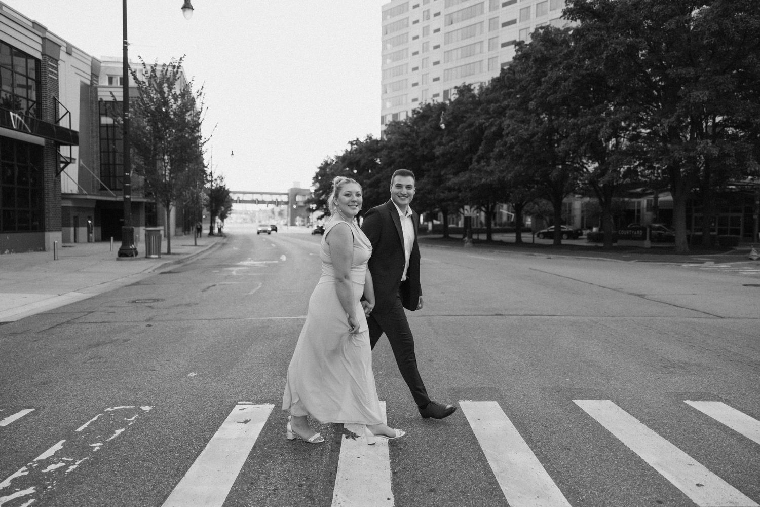 Urban engagement photography session on a city street with tall buildings.