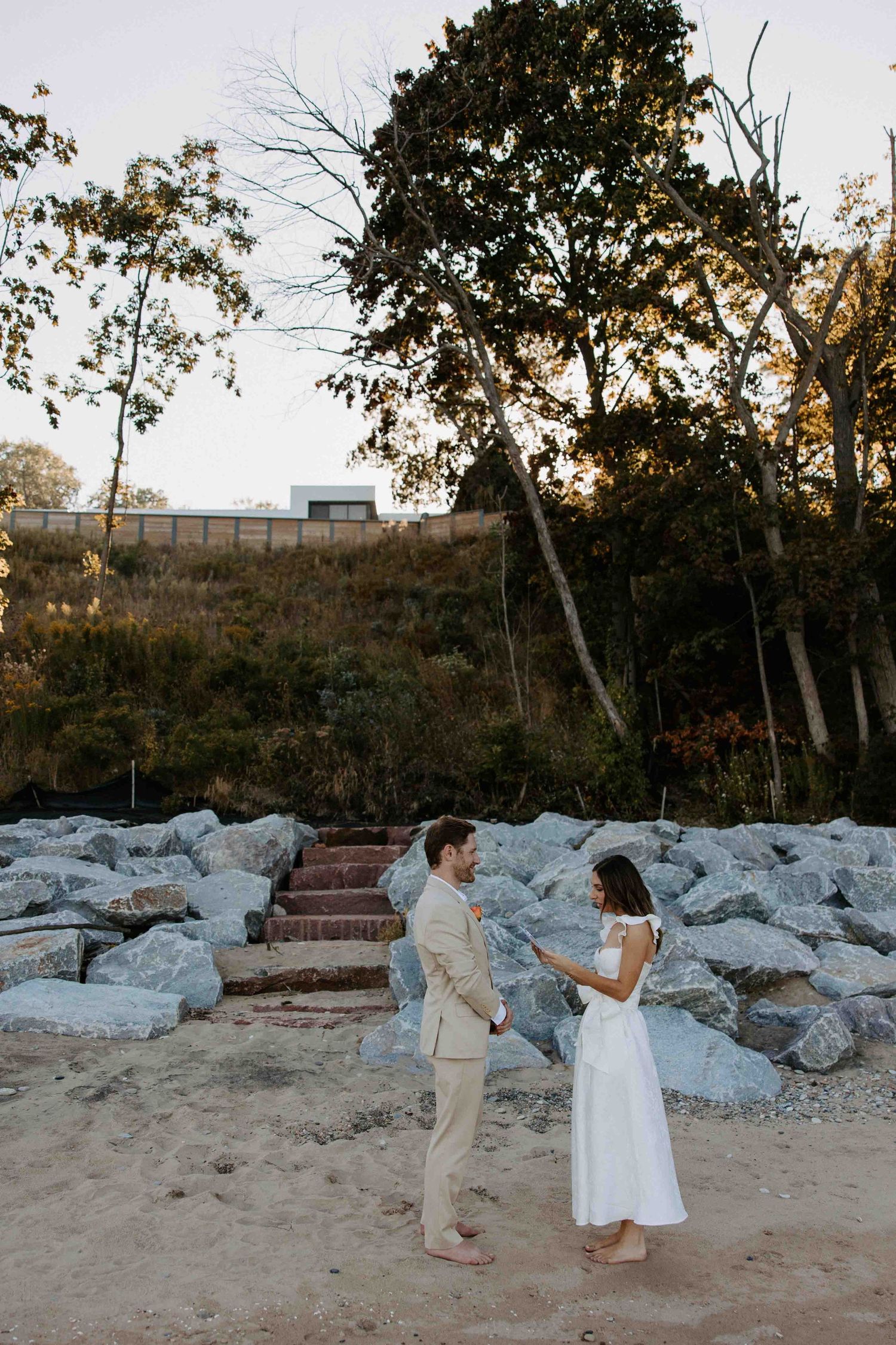 Couple shares a romantic moment on a rocky beach path during a sunset proposal.