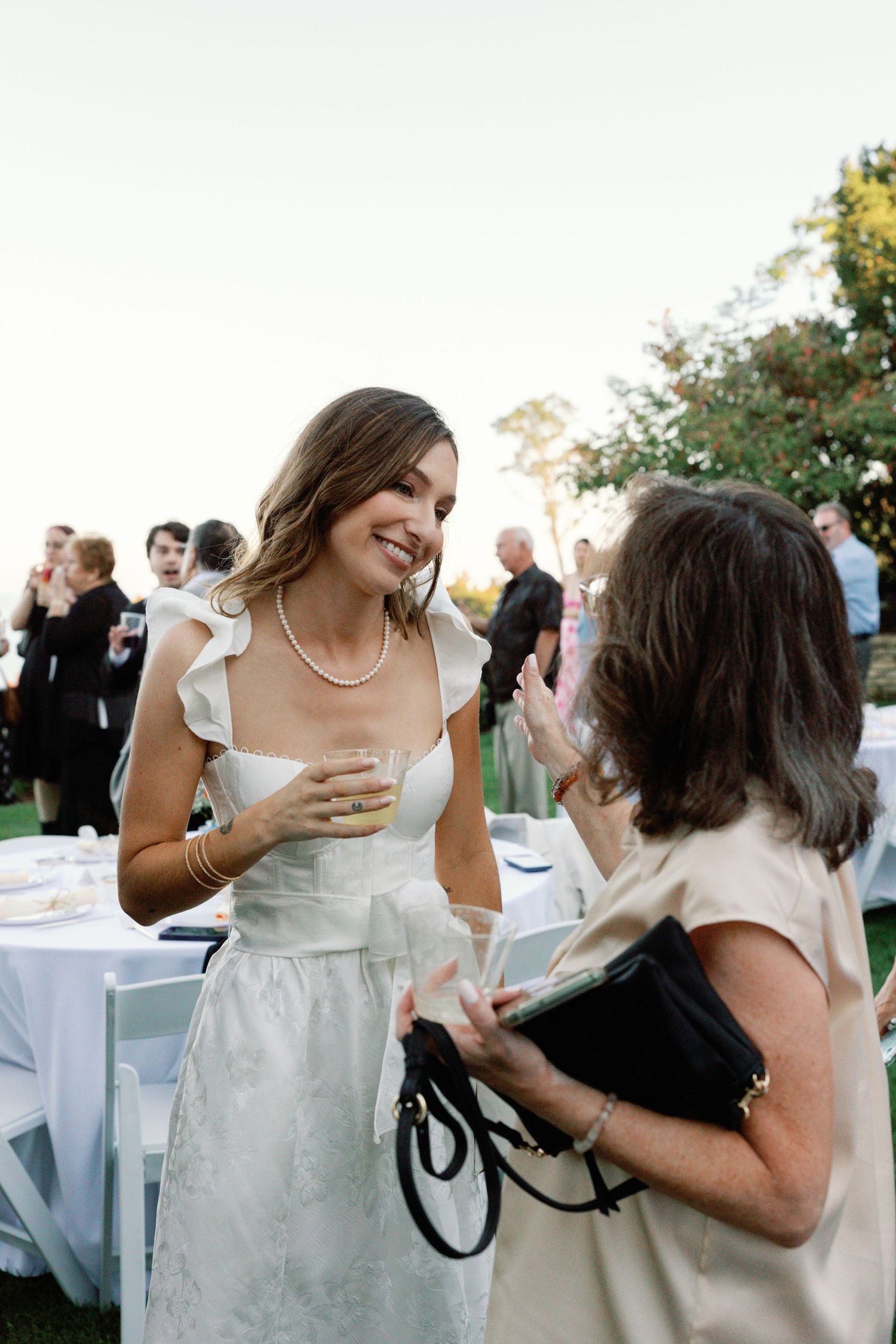 Joyful interactions between wedding guests at an outdoor reception with white tables.