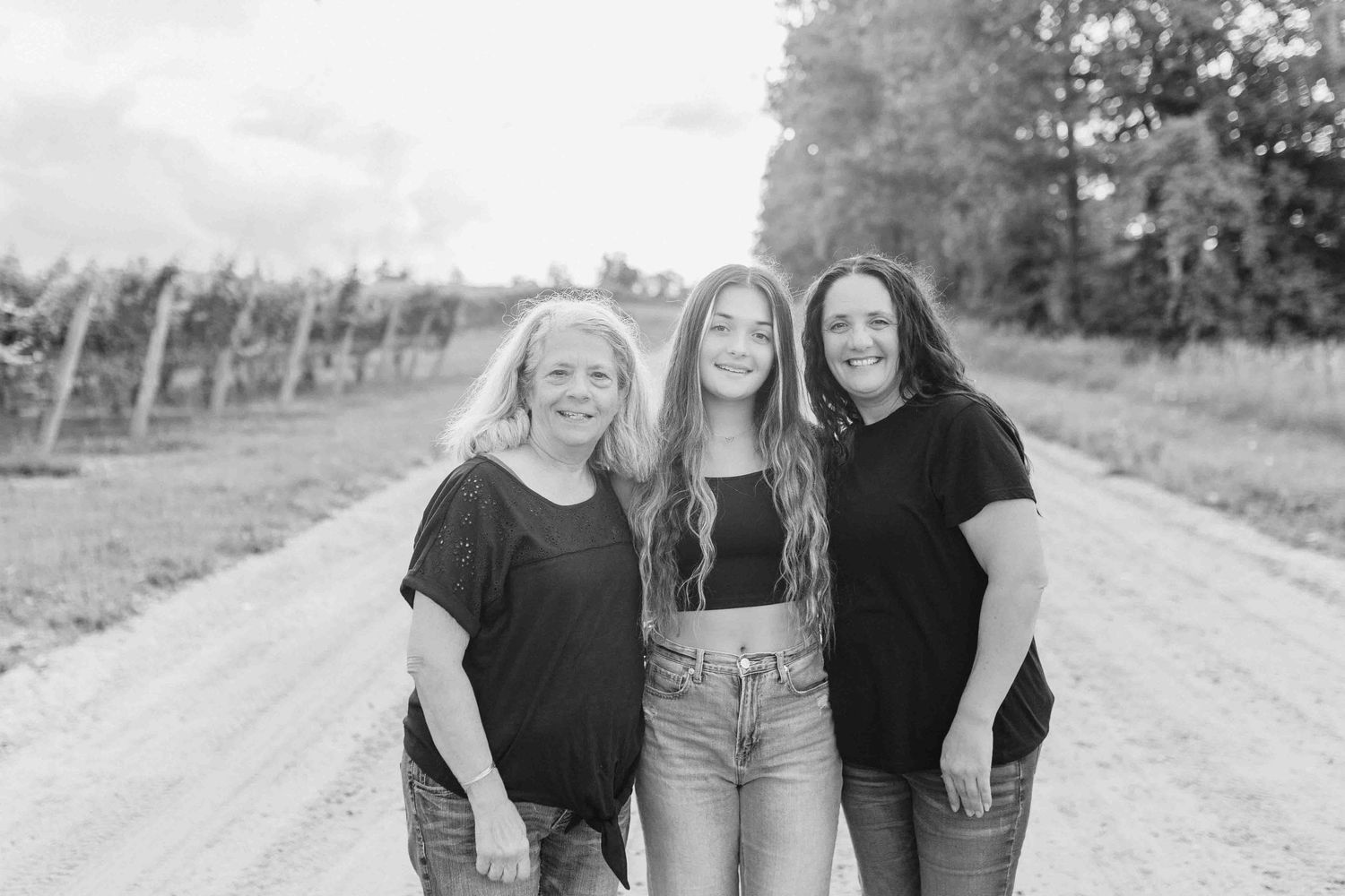Friends walking together on a dirt path through vineyard rows.